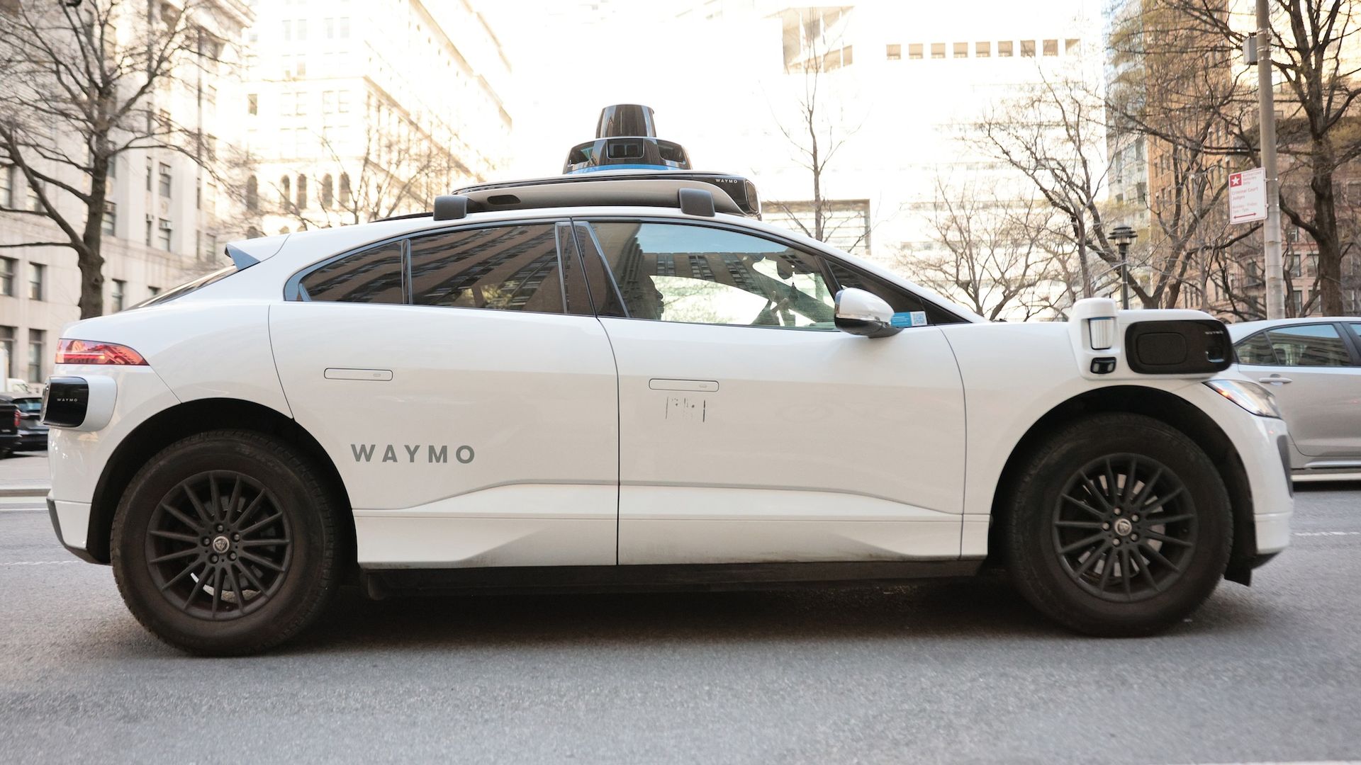 A white Waymo robo taxi on a New York City street.