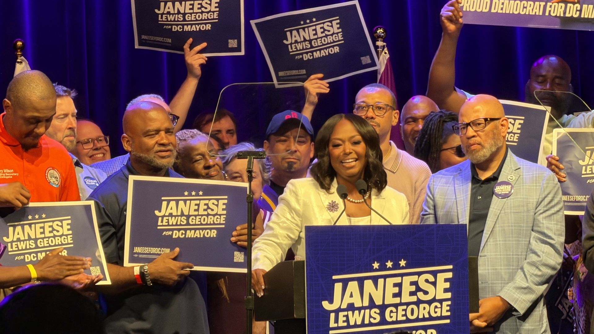 Janeese Lewis George addresses supporters at Howard Theatre with a group of union leaders and supporters behind her on stage