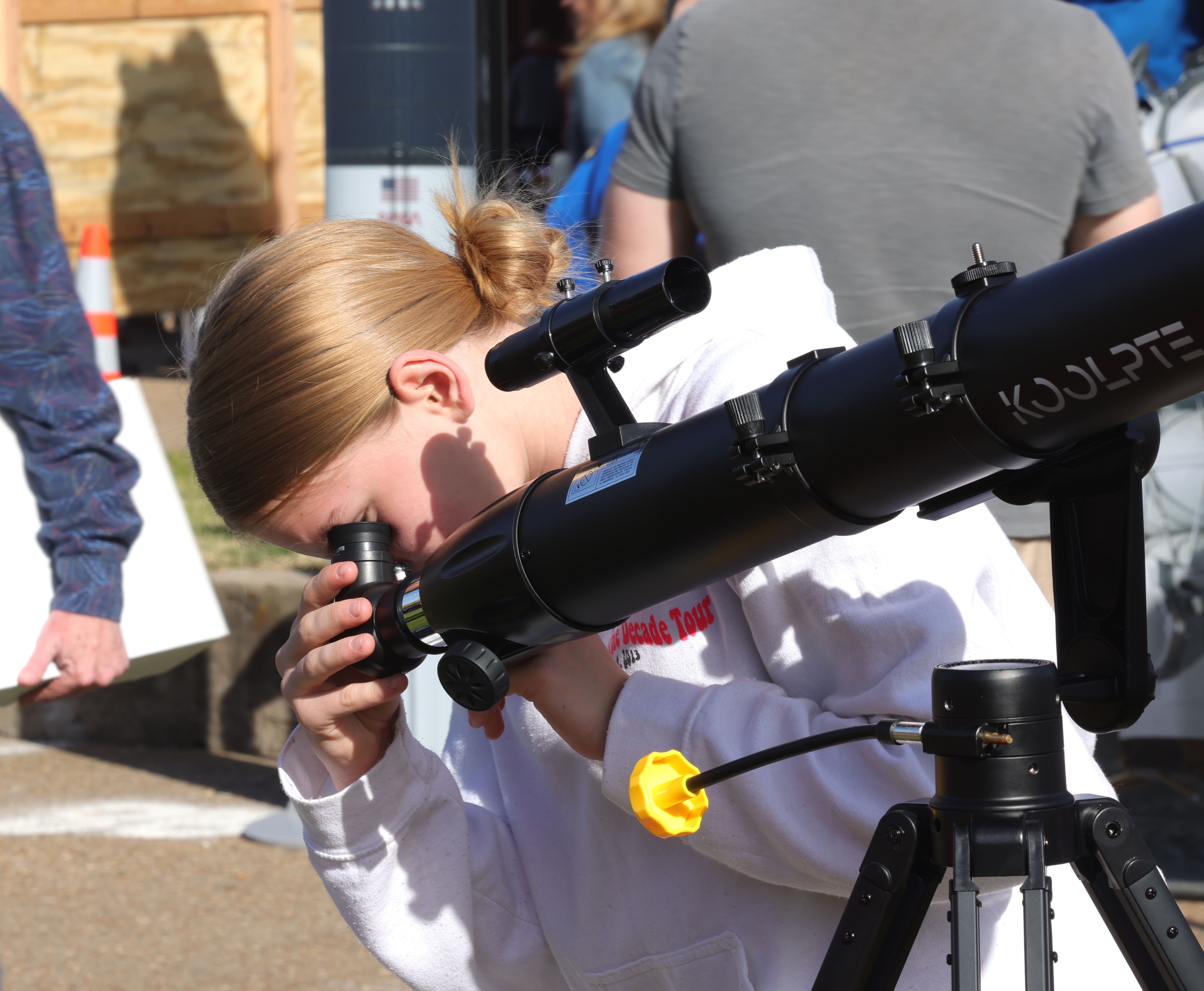 A young girl looks through a telescope. 