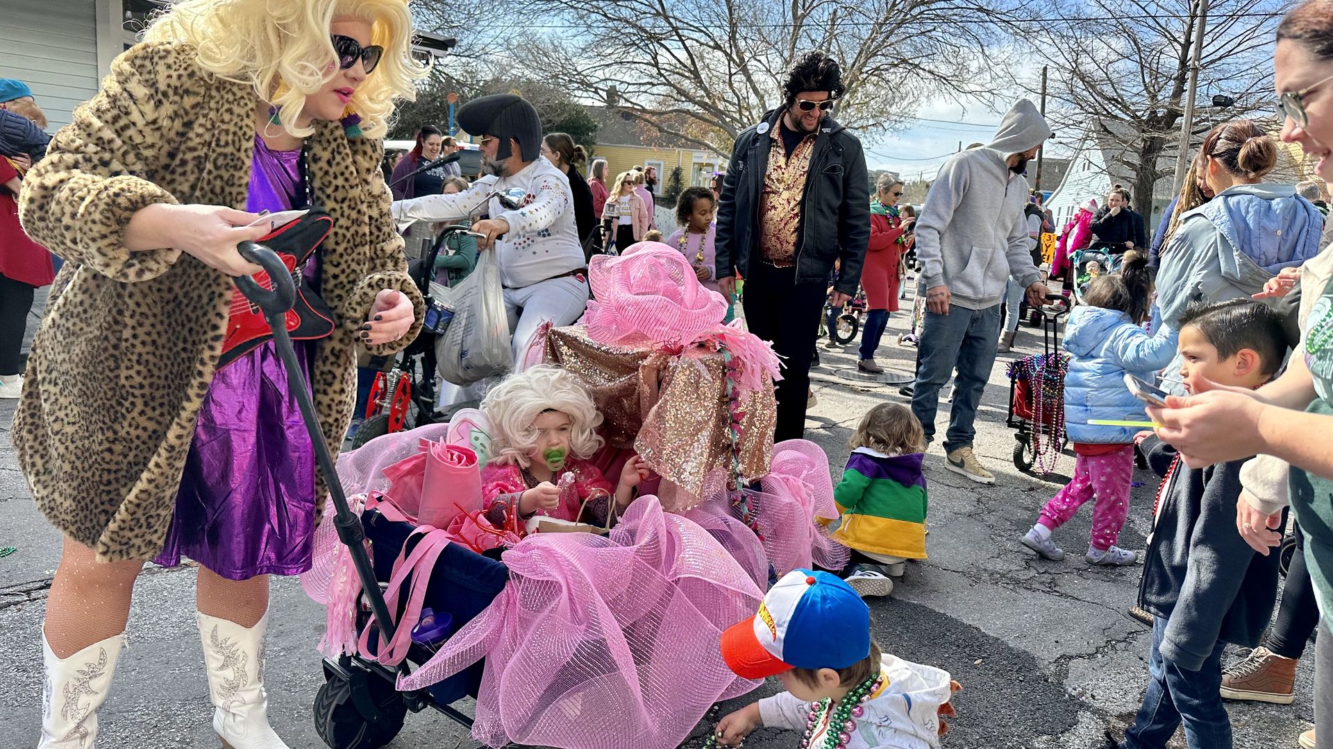 Photo shows a lady dressed as Dolly Parton with a baby in a festive wagon.