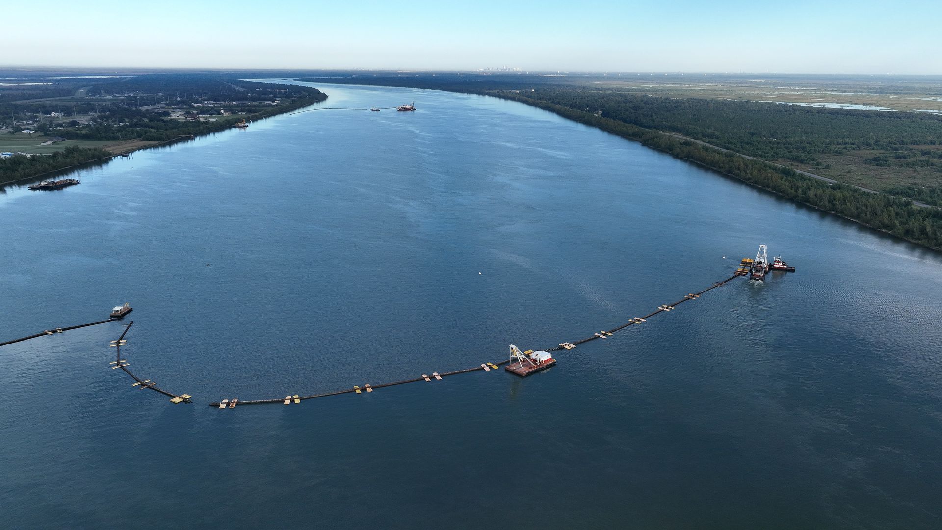 An aerial view of the Mississippi River, upon which booms stretch across the majority of the river as construction continues on an underwater sill.