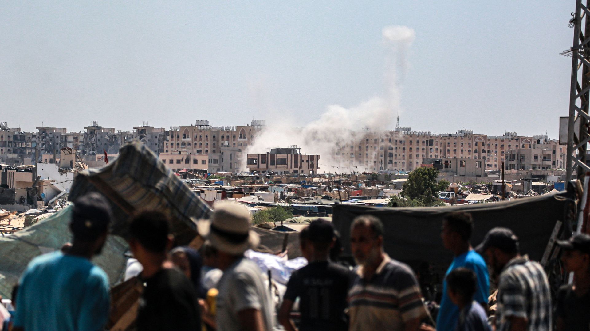 People look on as an Israeli strike creates a plume in the city of Khan Younis. 
