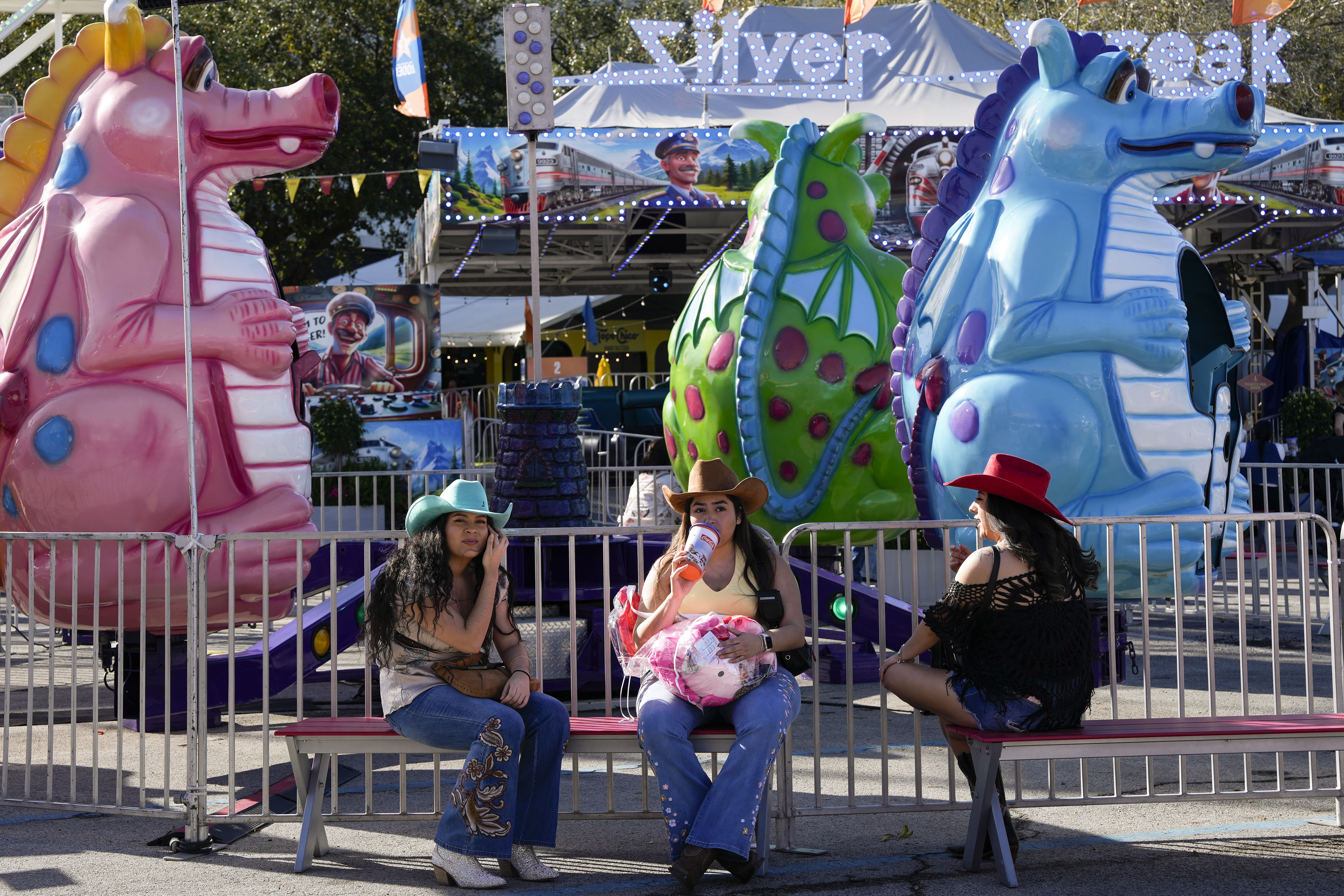 Photo of three women in western attire sitting on a bench. 