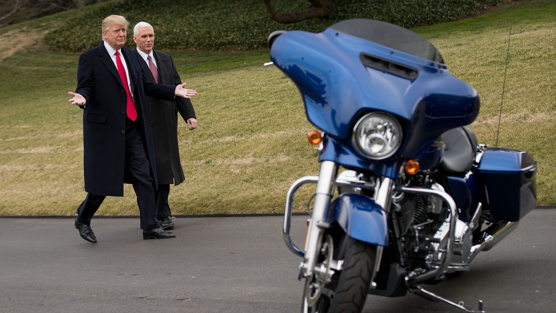 President Trump and VP Pence approach a Harley-Davidson motorcycle.