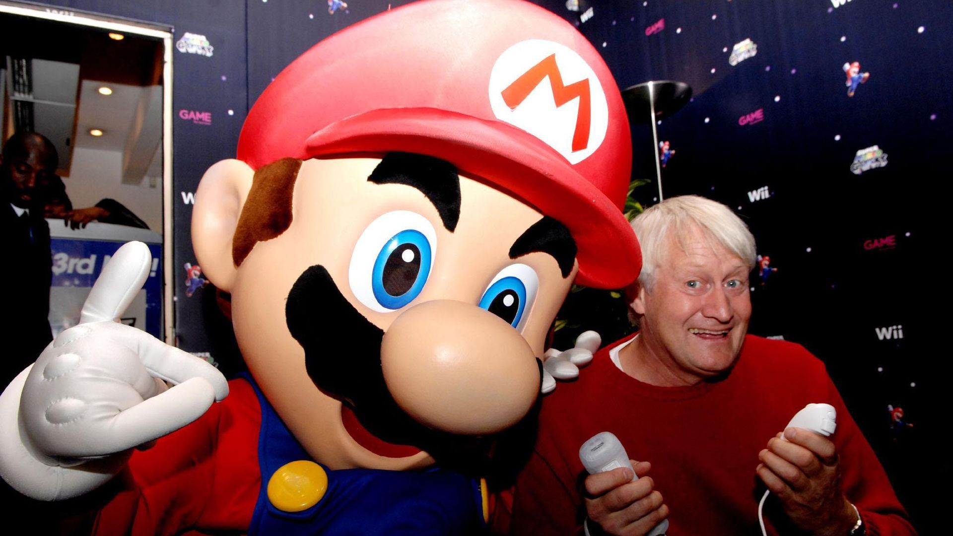 Photo of person in a Super Mario costume standing next to Charles Martinet