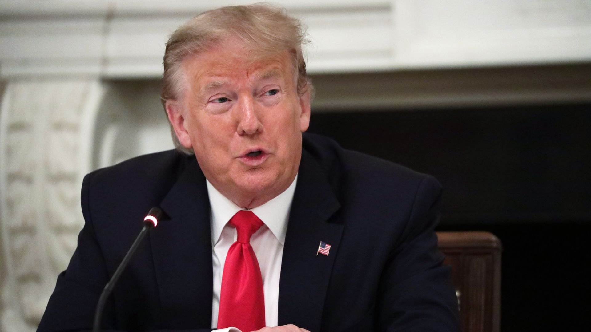 President Trump speaking into a microphone during a roundtable discussion