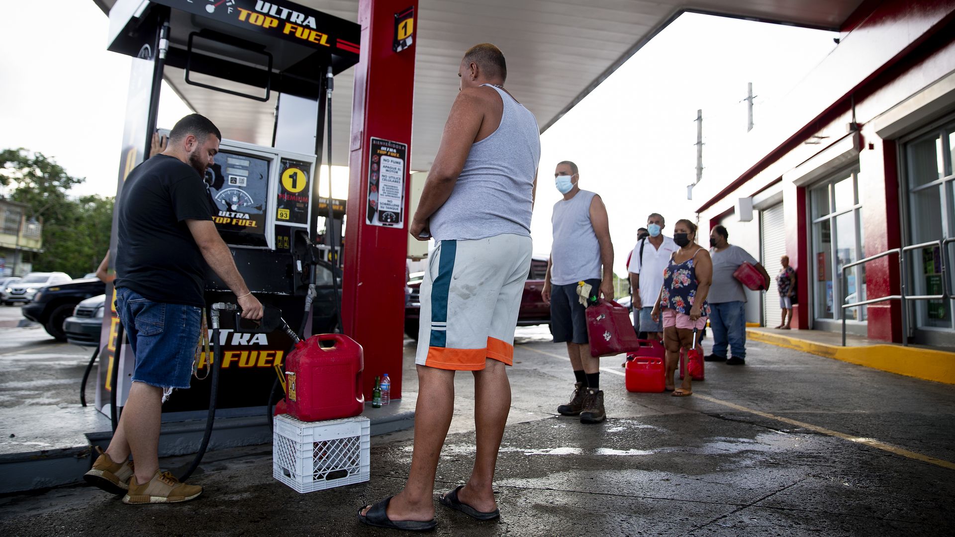 Photo of people waiting in line with jugs to fill up diesel at a gas station