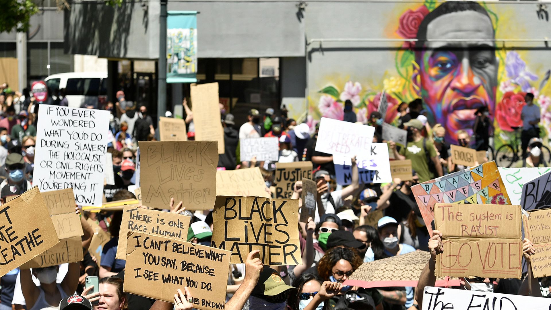 Marchers walk by a mural of George Floyd painted on a wall along Colfax Avenue on June 7, 2020 in Denver. Photo: Helen H. Richardson/Denver Post via Getty Images