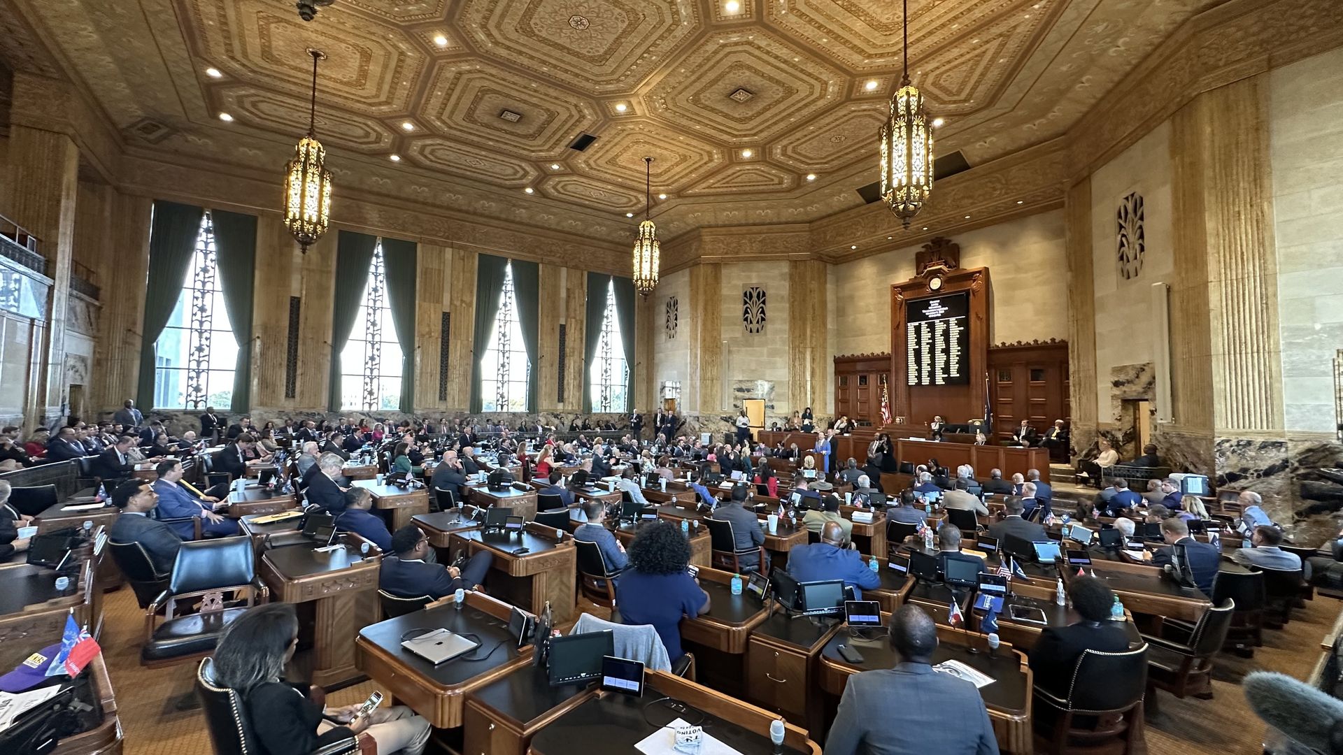 A wide-angle view of the Louisiana House of Representatives in session while Gov. Jeff Landry speaks. Dozens of people sit at their desks and look toward the front of the chamber.