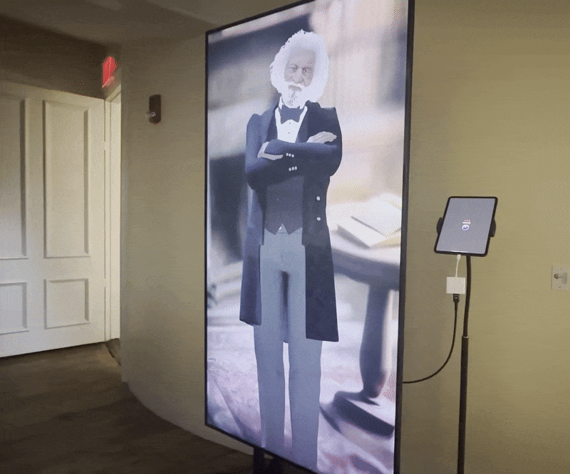 A gif showing a 2D, AI-driven hologram of Frederick Douglass on a screen in the African Meeting House's sanctuary.