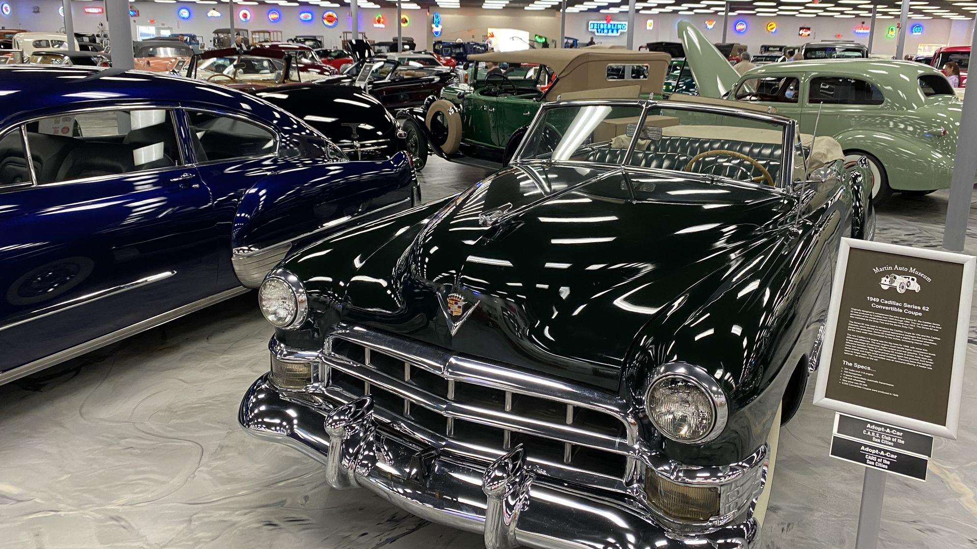 Rows of classic cars on display in a large museum showroom.