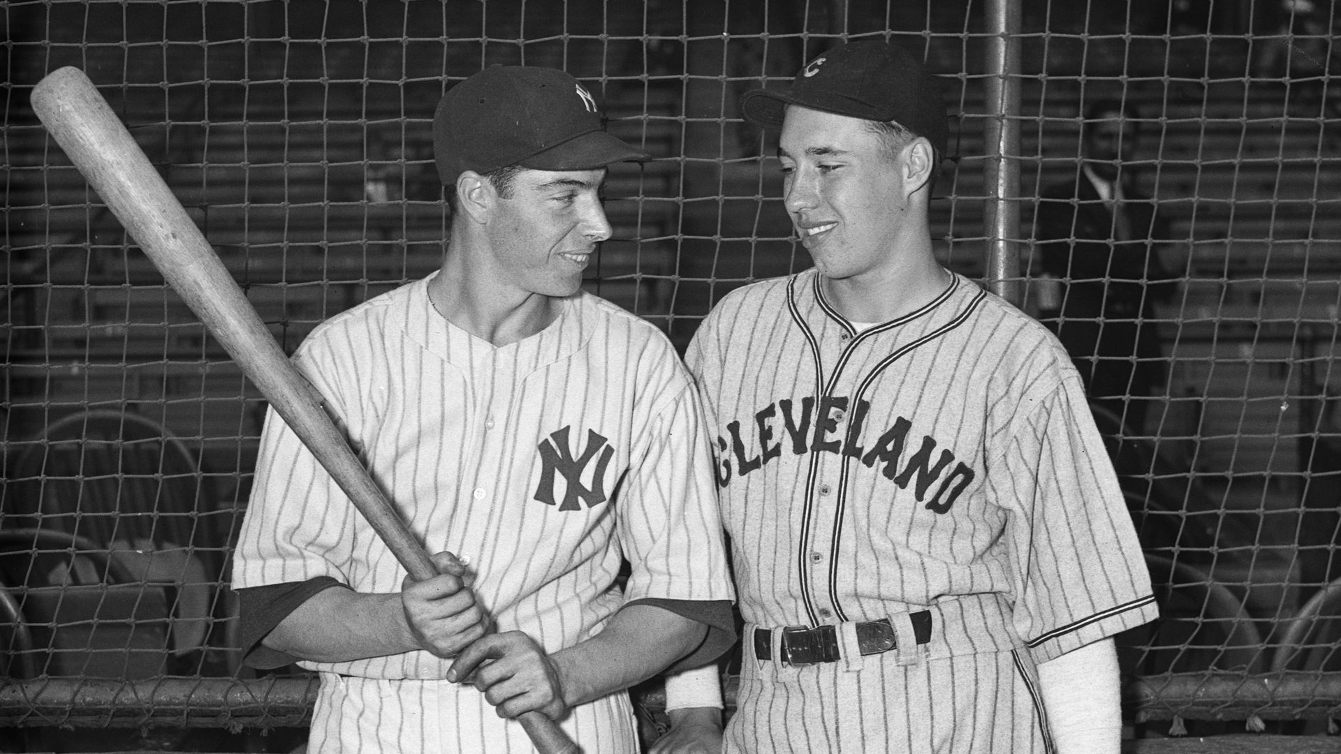 Baseball players Joe DiMaggio and Bob Feller stand next to each other near home plate. 
