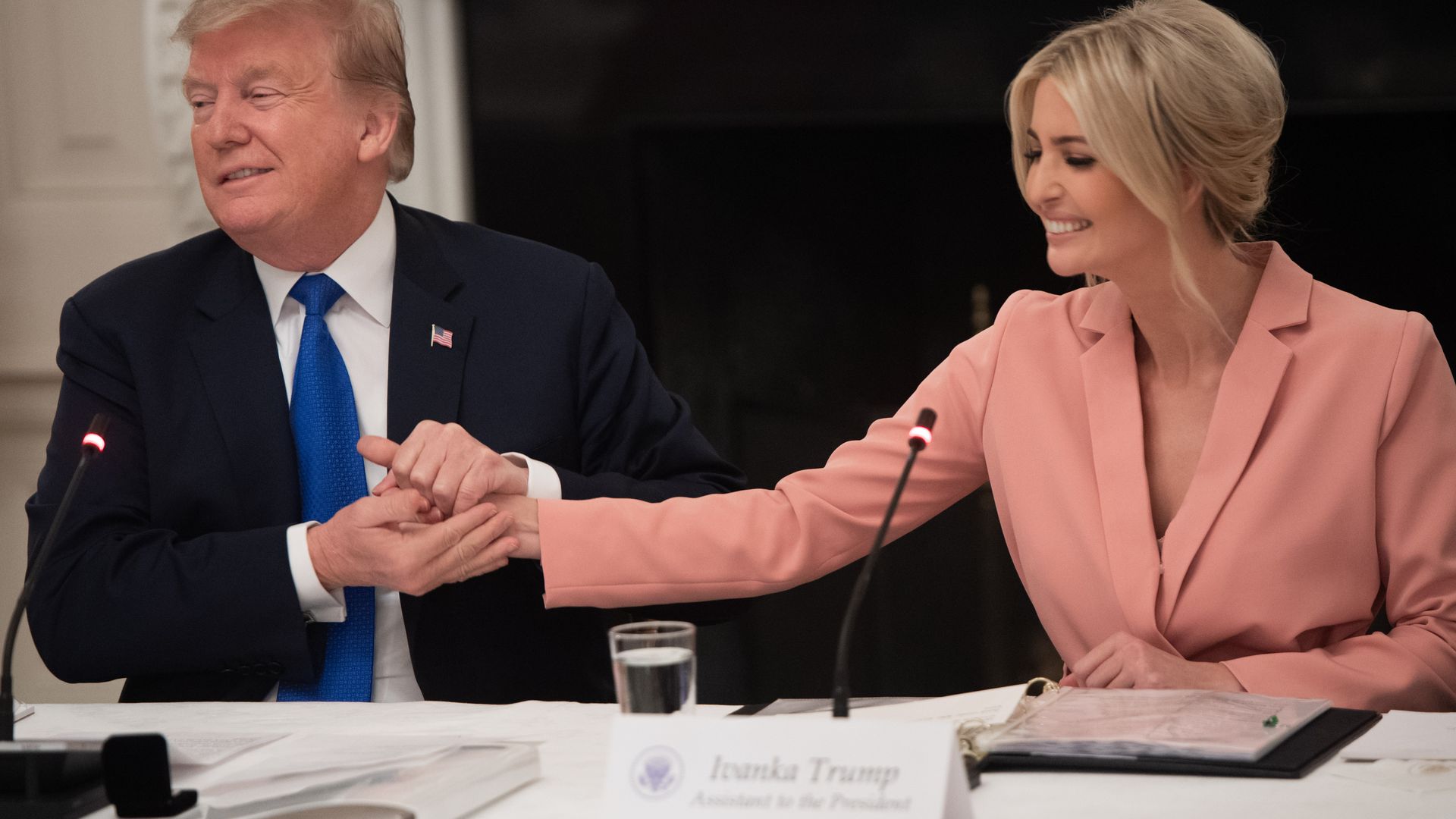 In this image, Ivanka holds her father's hand over a table at a meeting.