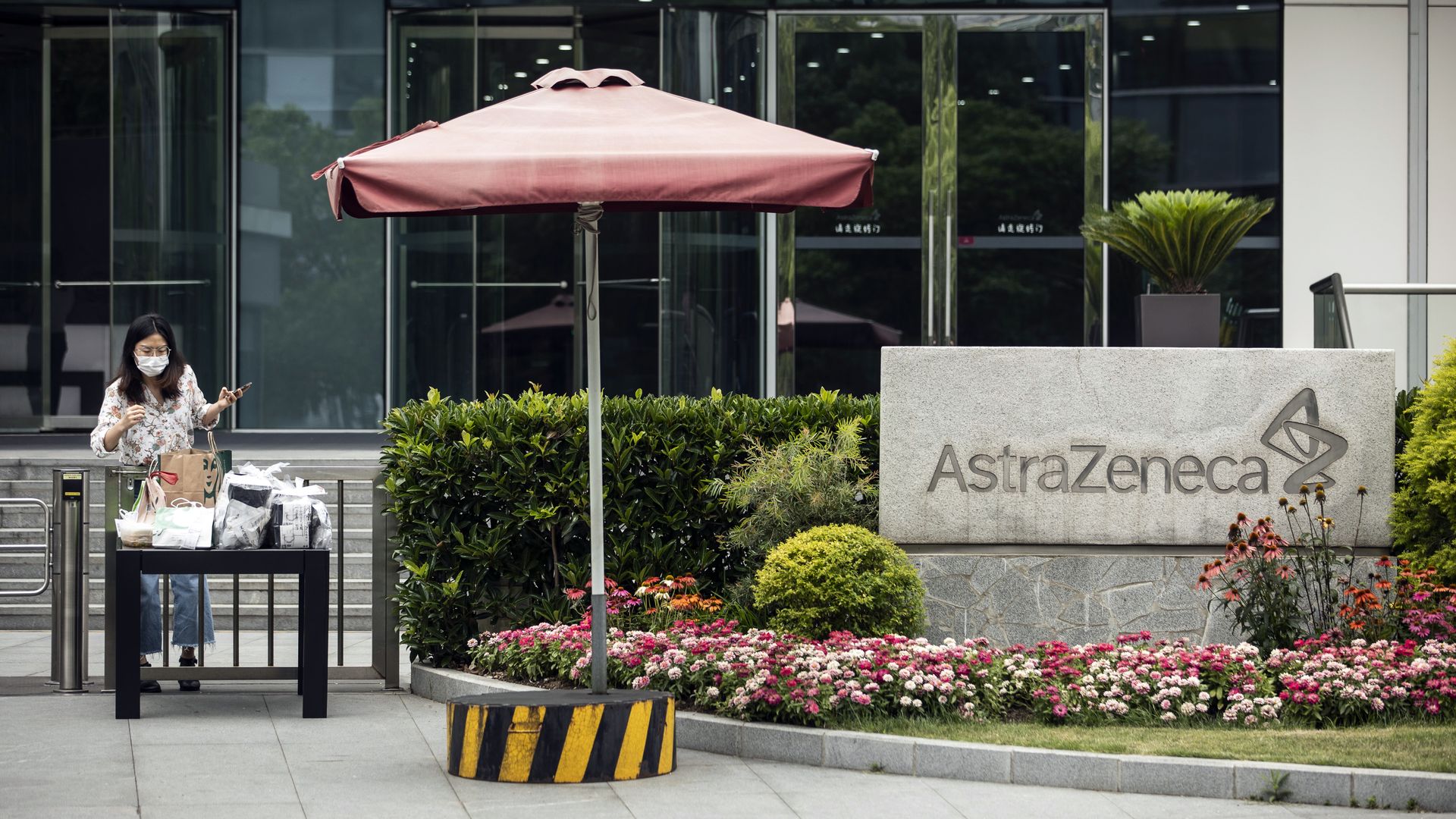 An employee wearing a protective mask collects a lunch delivery from a table outside an AstraZeneca Plc research and development facility in Shanghai, China, on Monday, June 8, 2020.