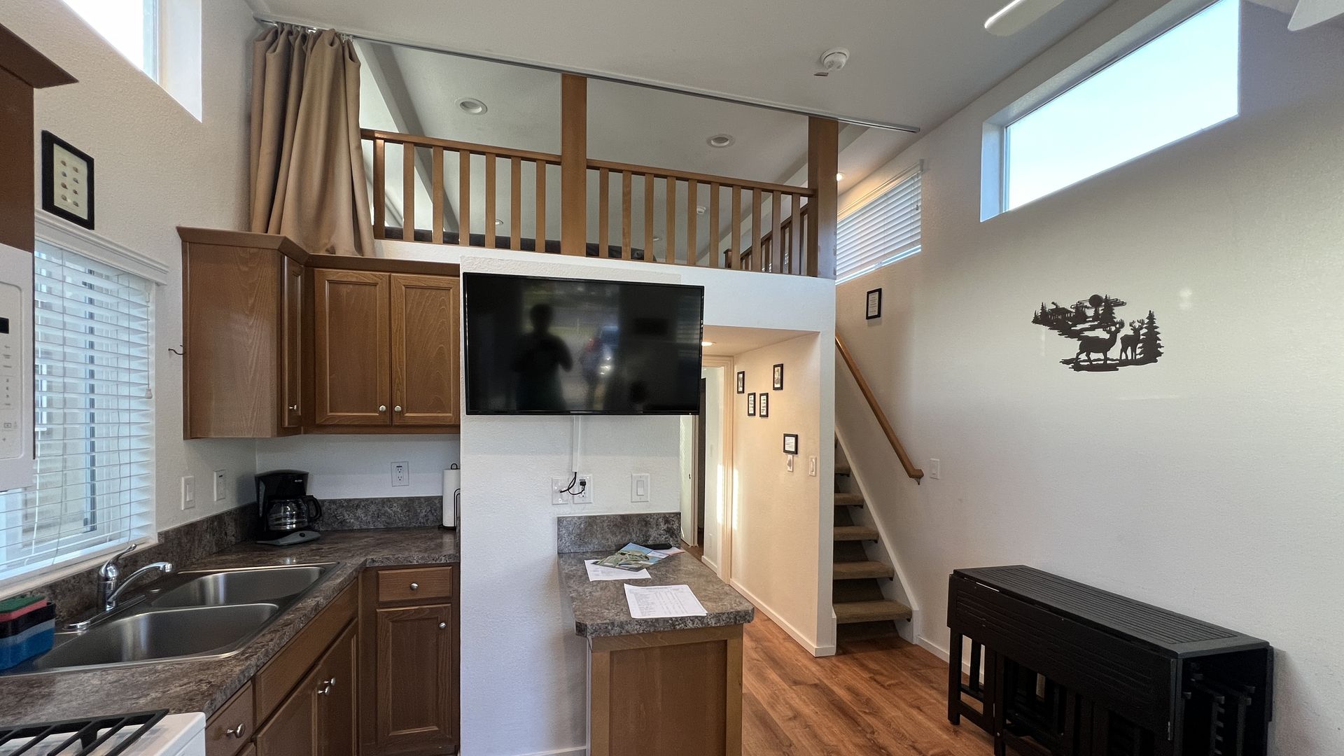 A view of a tiny apartment with a galley kitchen and lofted living space.