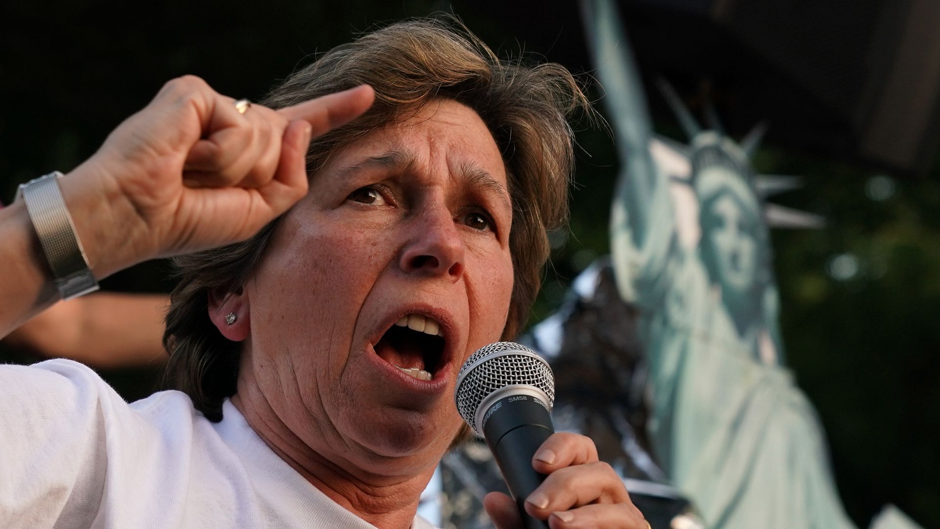 President of American Federation of Teachers Randi Weingarten speaks at an event in Washington, D.C. with the image of the Statue of Liberty in the background. 