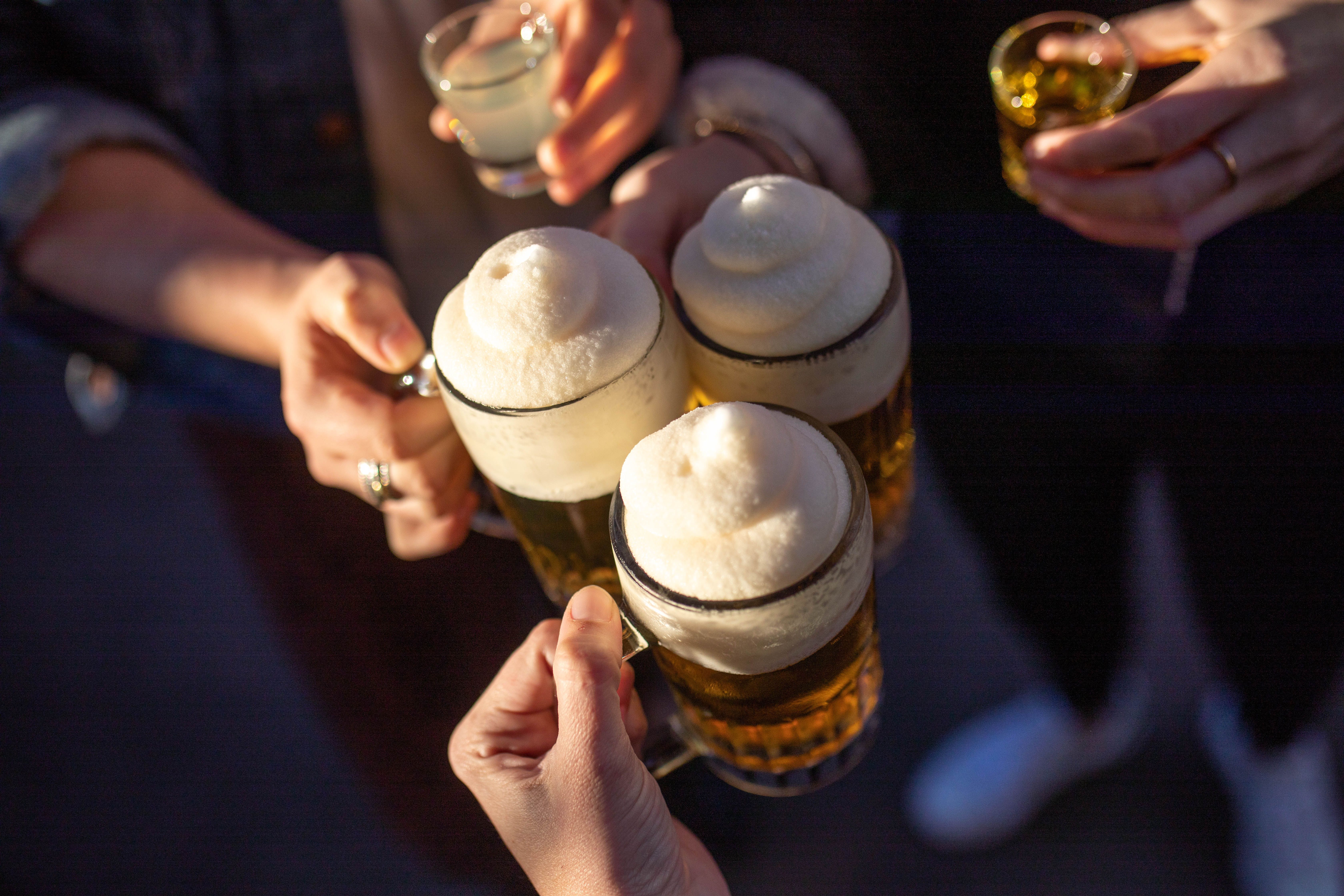 People clink three beer glasses with foam