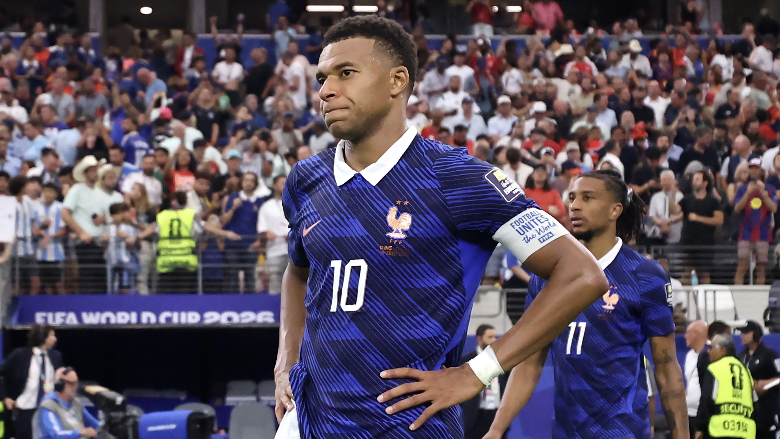 Kylian Mbappé looks out with his arms over his hips