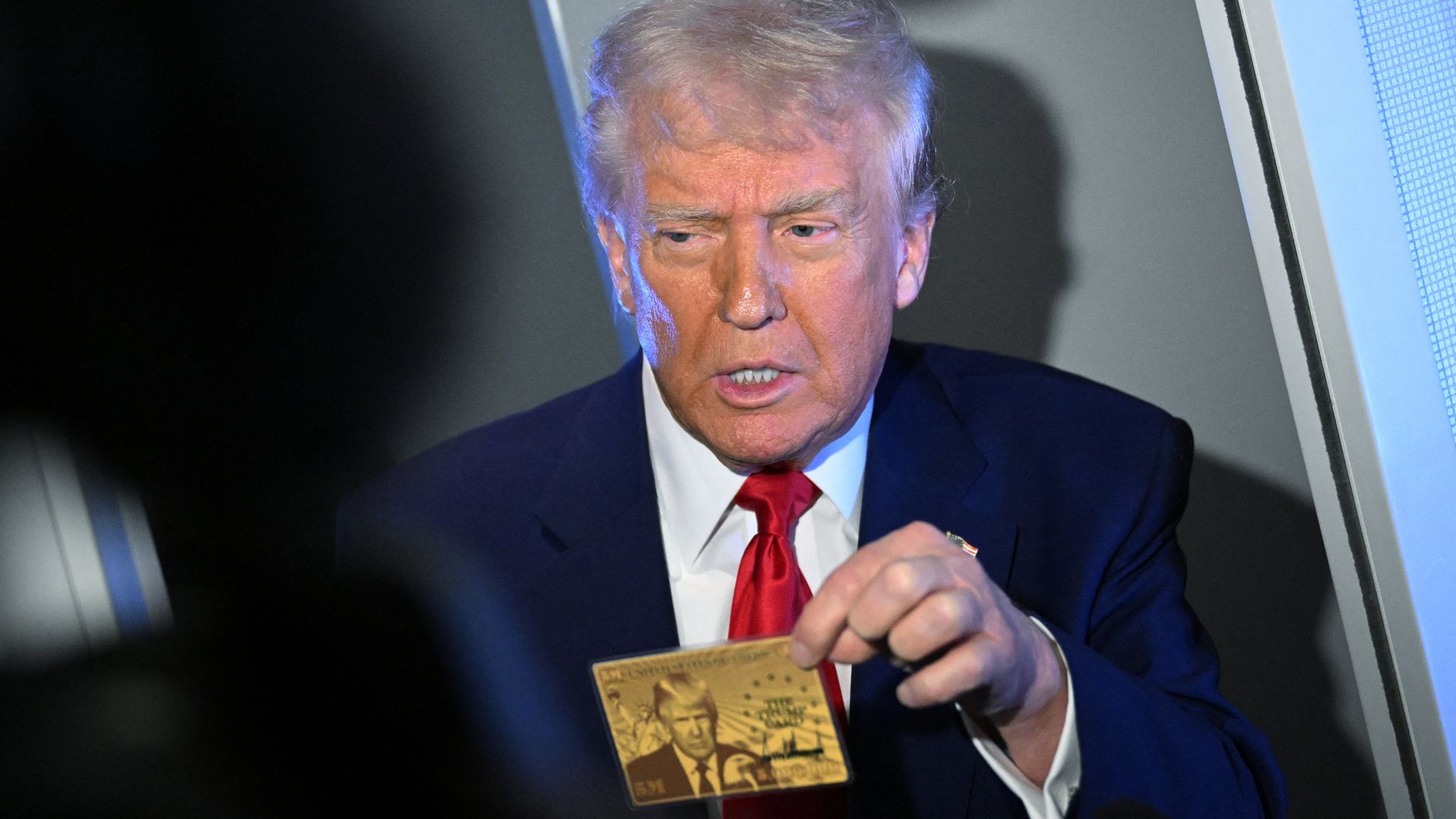 President Donald Trump holds the $5 million dollar Gold Card as he speaks to reporters while in flight on board Air Force One, en route to Miami, Florida on April 3, 2025. Trump is travelling to the Trump National Doral Golf Club before going to his Mar-a-Lago Resort