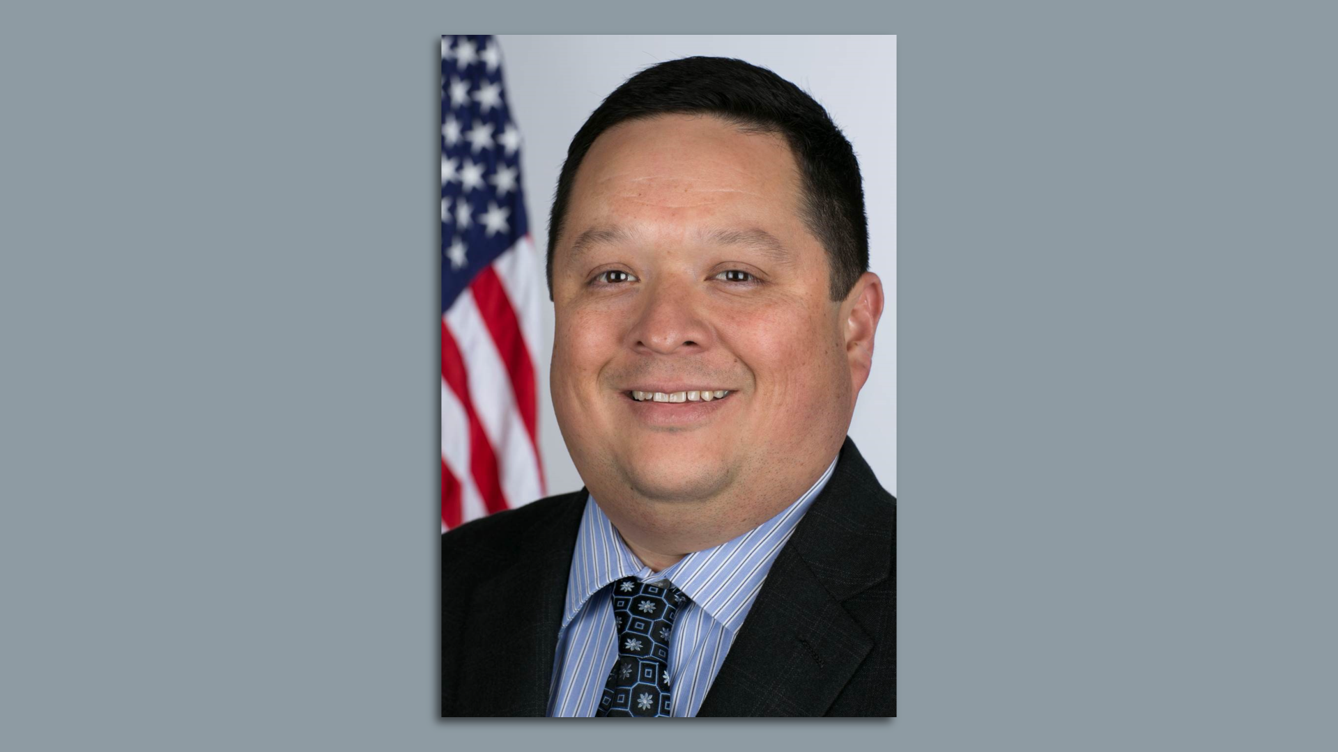 Adrian Saenz poses while next to an American flag