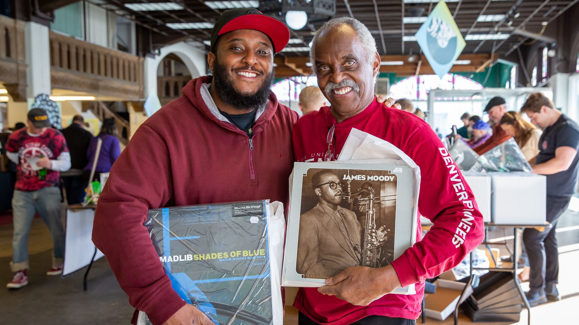 Two men posing for a photo together holding their vinyl records
