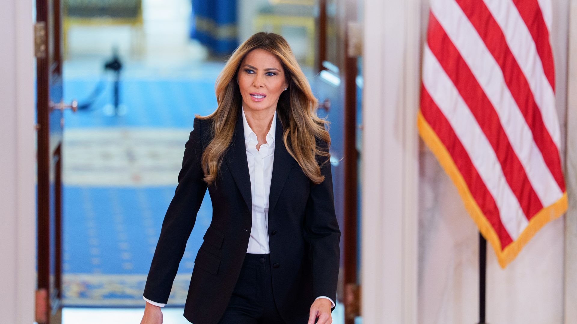 Melania Trump wears a black suit jacket and white shirt. 