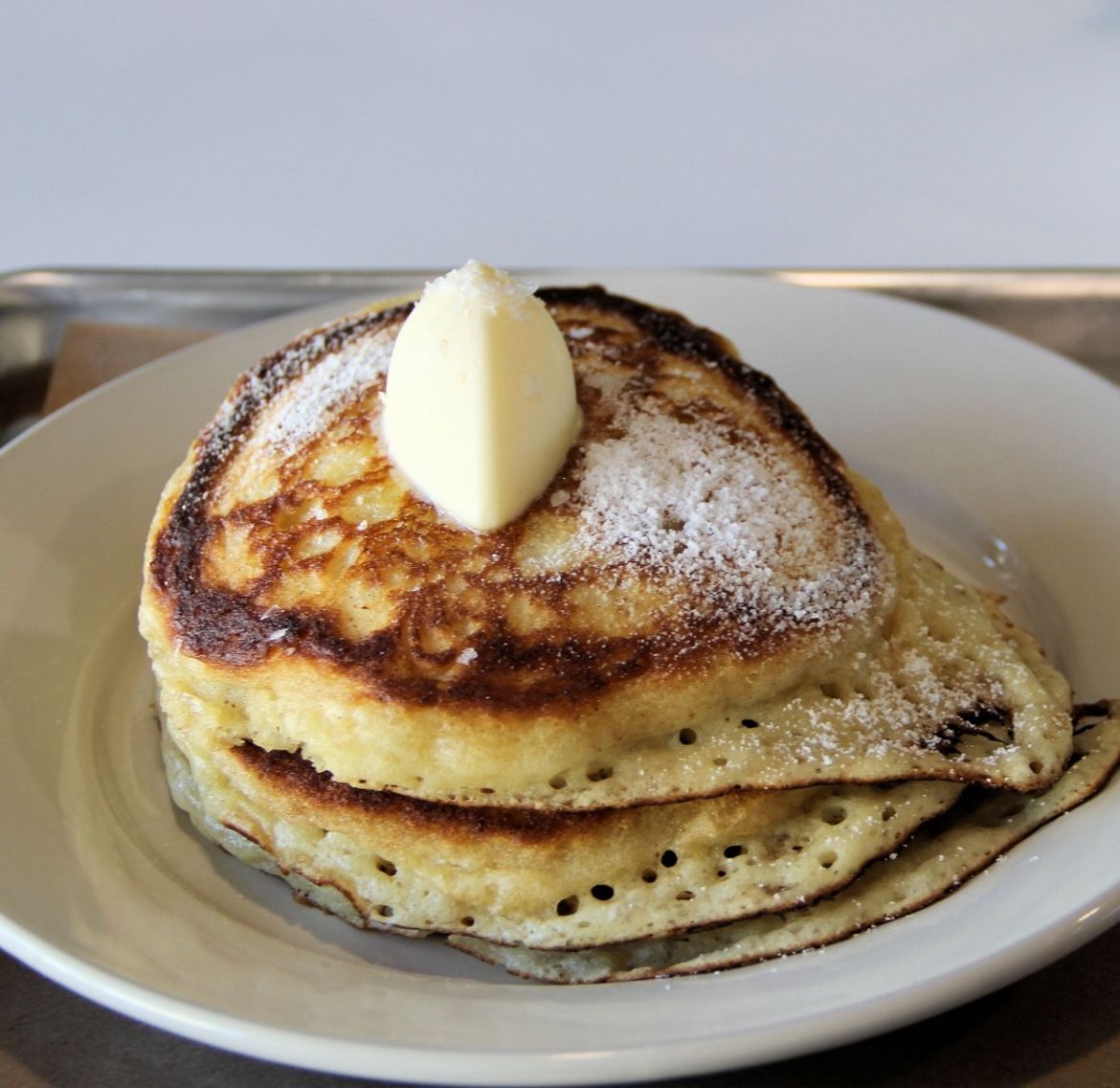 A stack of thick pancakes with a dallop of butter.