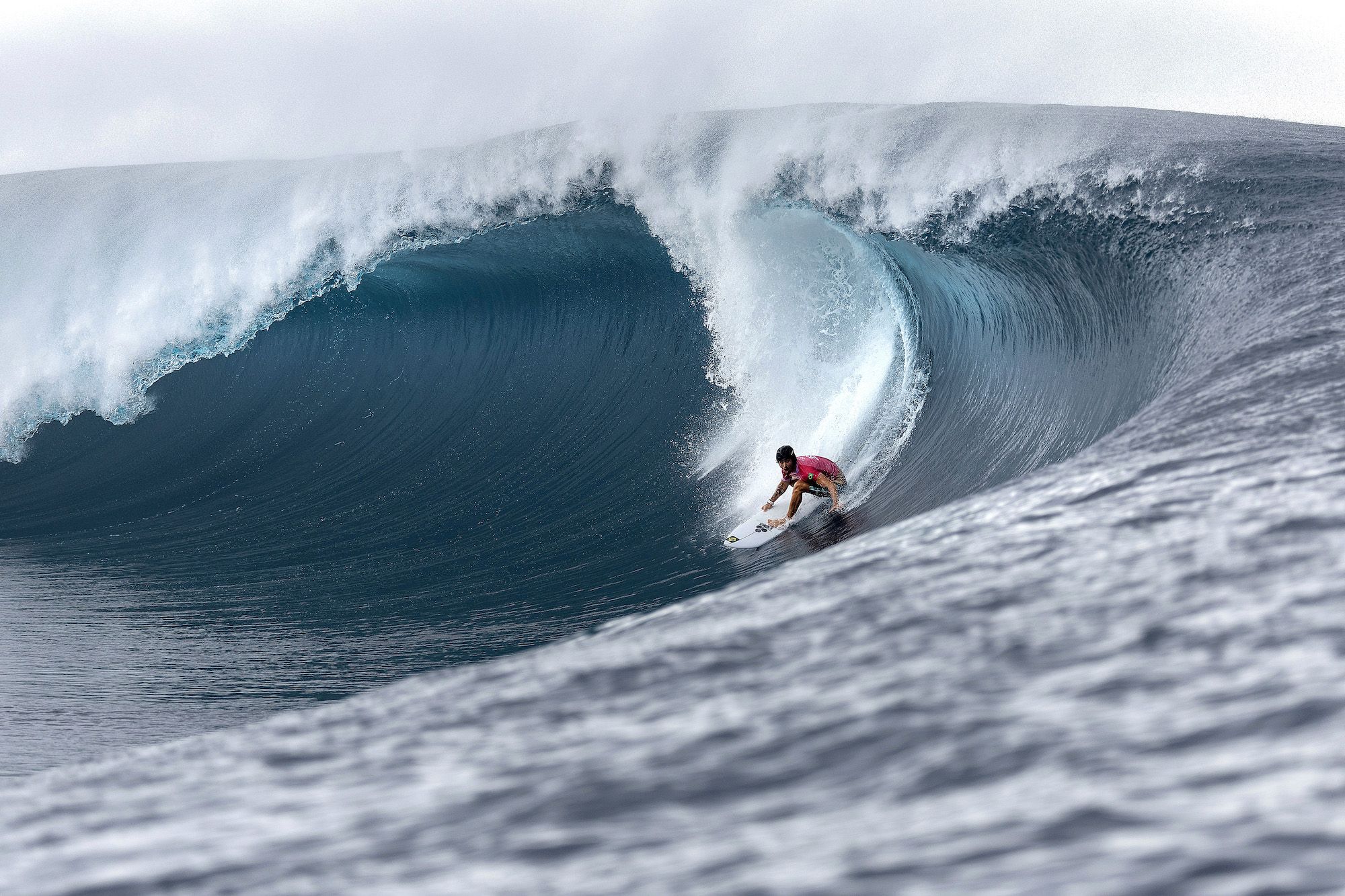 A surfer rides a barreling wave.