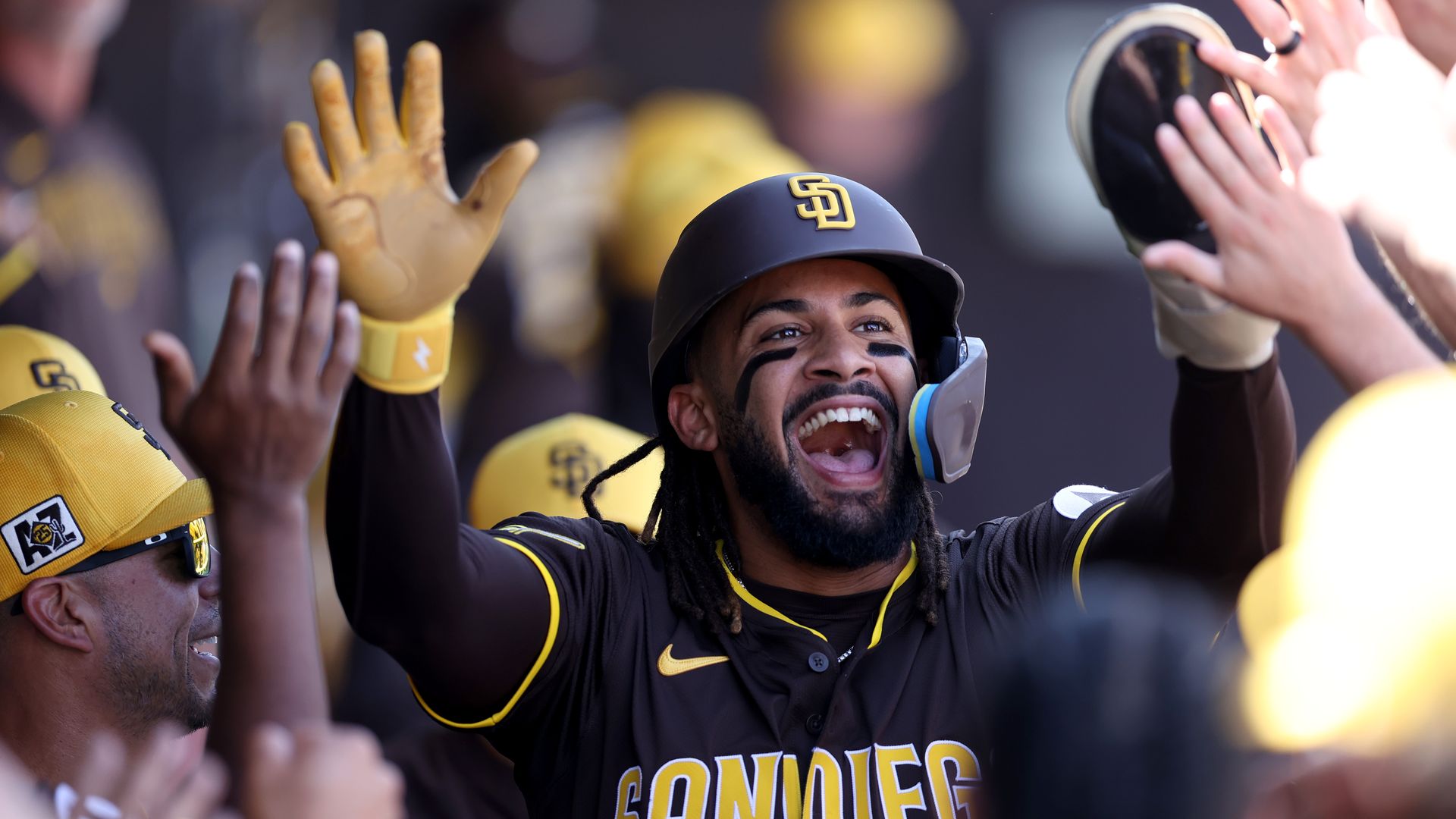 San Diego Padres player Fernando Tatis Jr. high-fives his teammates in the dugout.