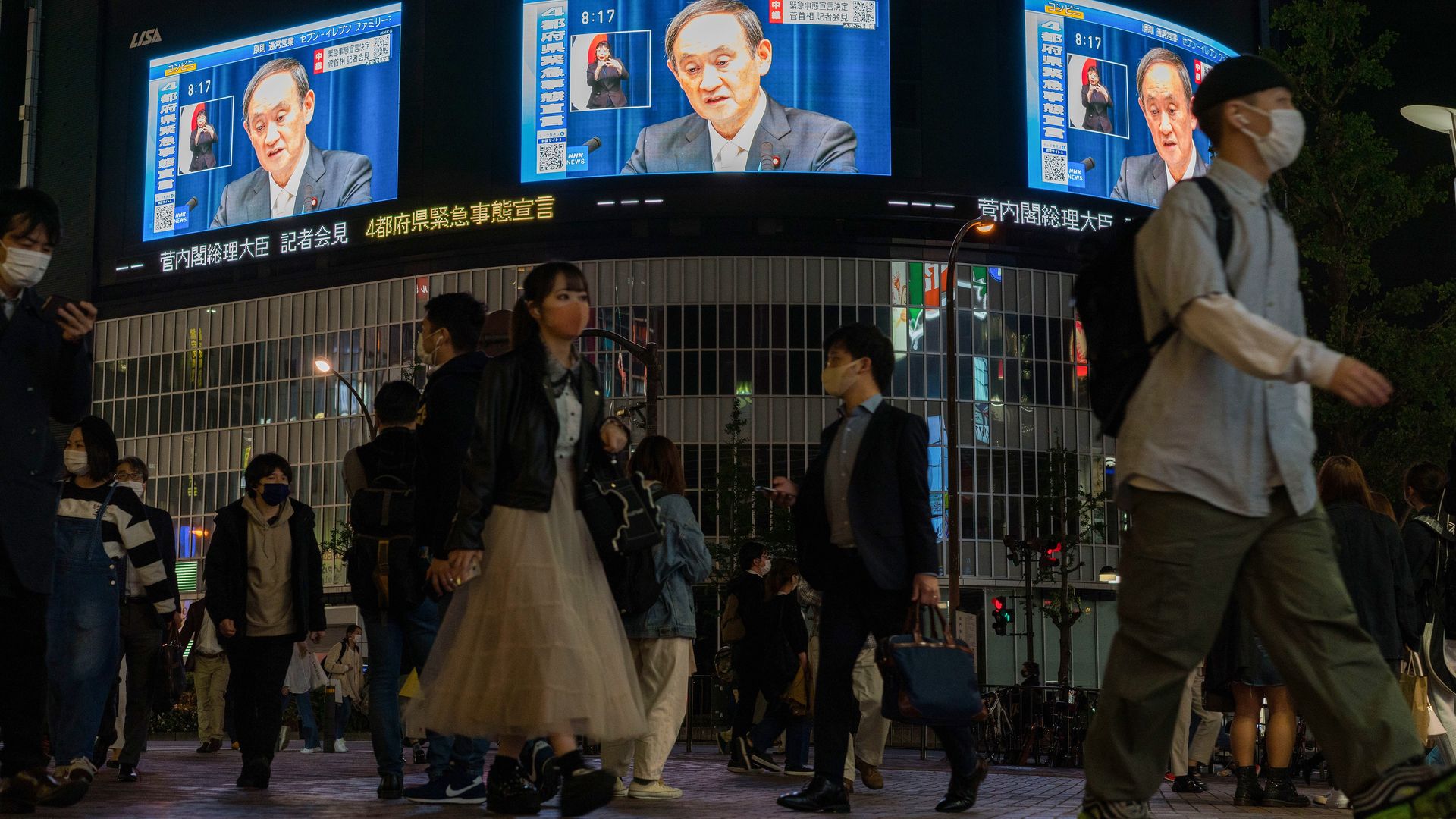 Japan's Prime Minister Yoshihide Suga is shown on outdoor screens during a press conference as he declares a state of emergency over COVID-19 in Tokyo, Japan on April 23