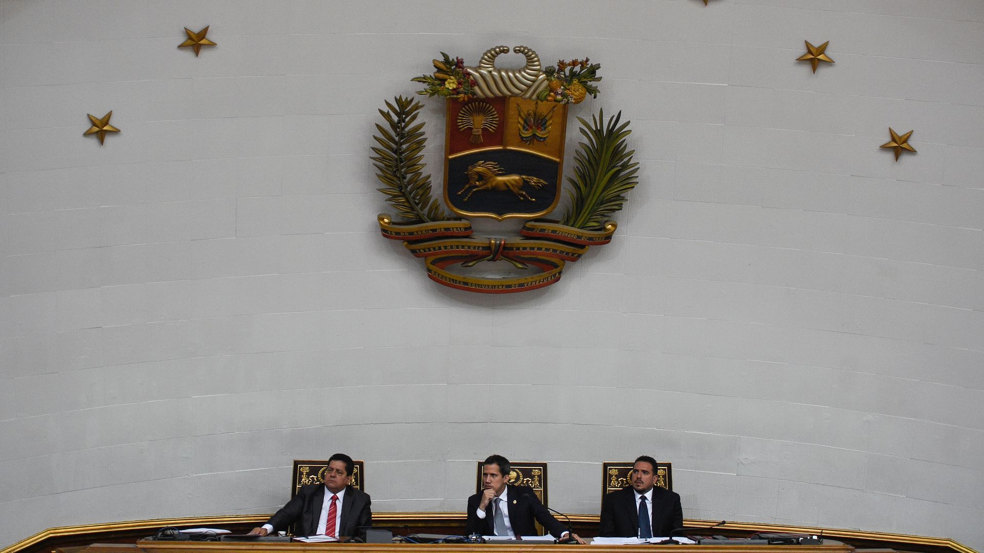 Juan Guaido sits with two other men at the National Assembly in Venezuela.
