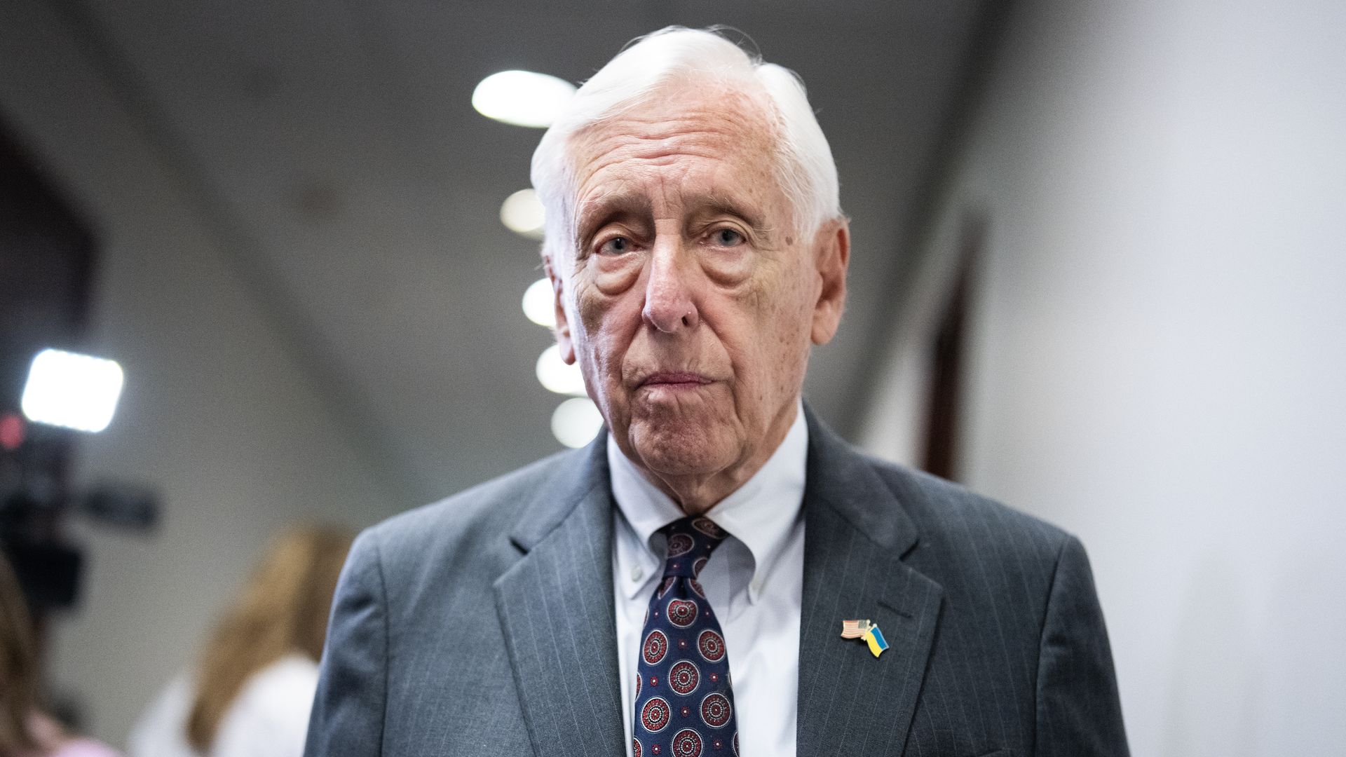 Steny Hoyer wearing a gray pinstripe suit and standing in a white hallway.