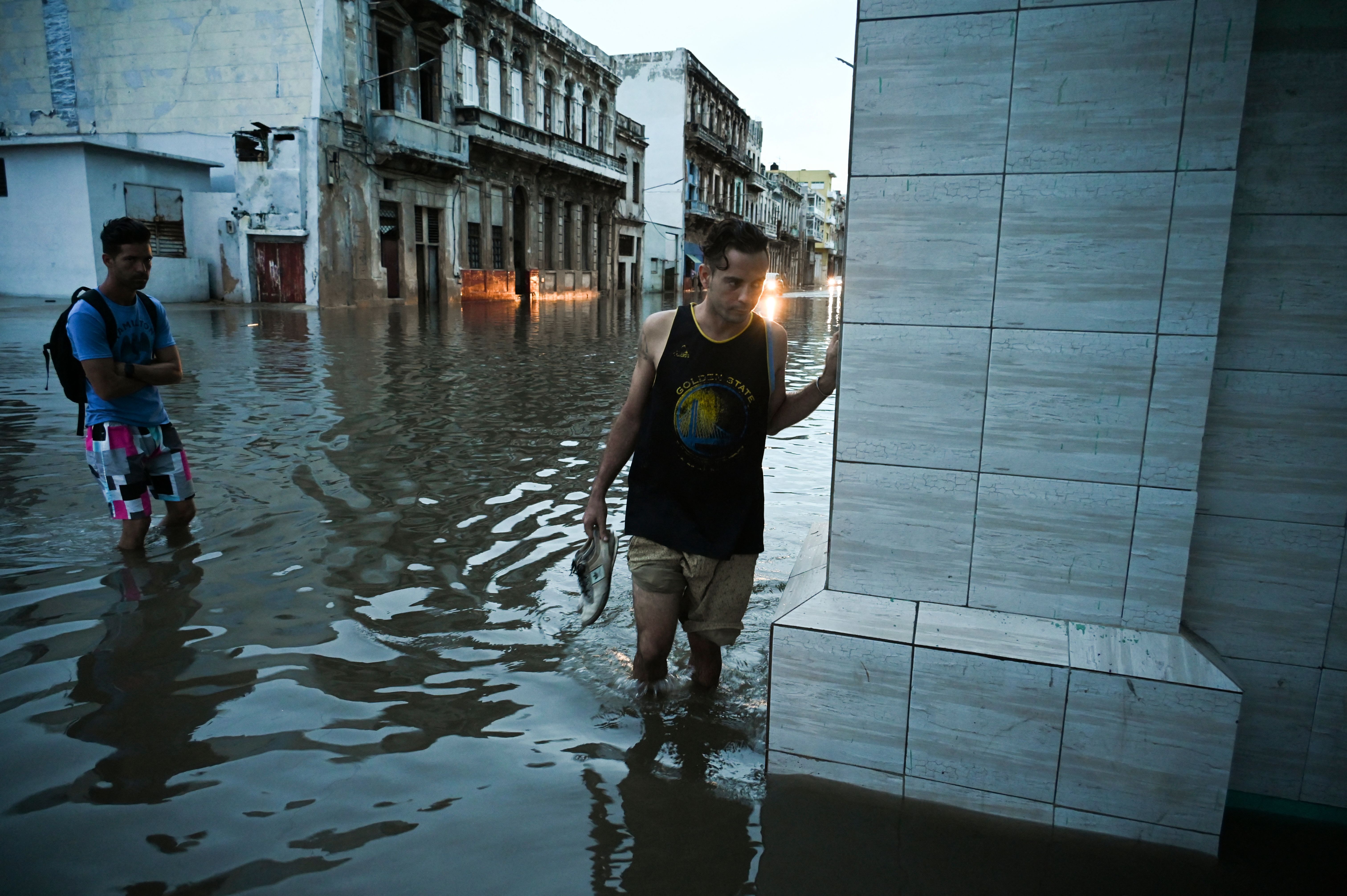 two people walking through a flooded street in Havana, Cuba