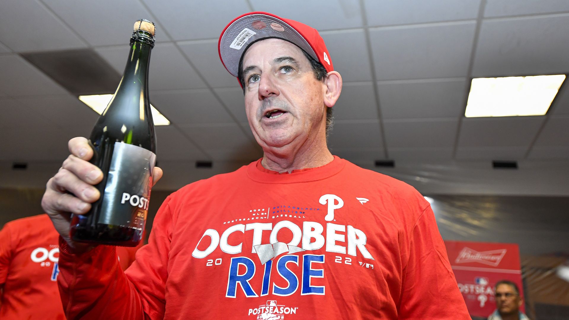 Phillies manager Rob Thomson holds up a bottle of champagne in the locker room after his team clinched a playoff berth. 