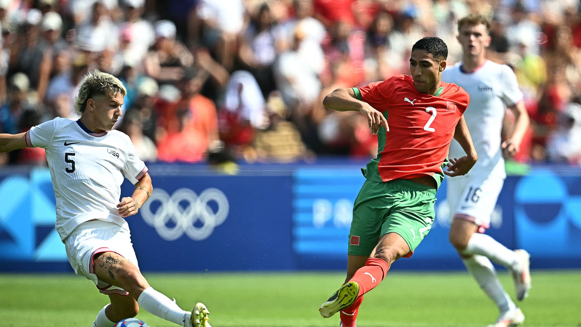 Morocco's defender #02 Achraf Hakimi (R) shoots and scores his team's third goal during the men's quarter-final football match between Morocco and the USA at the Paris 2024 Olympic Games at the Parc des Princes in Paris on August 2, 2024. (Photo by Paul ELLIS / AFP) (Photo by PAUL ELLIS/AFP via Gett