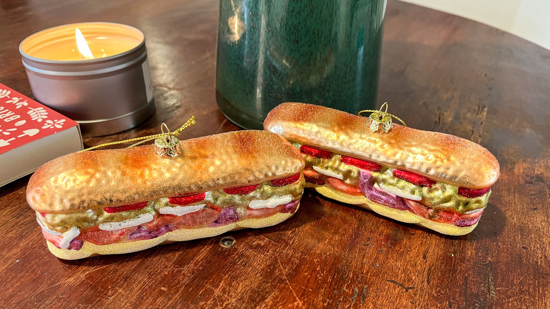 Two hoagie ornaments in front of a lit candle.