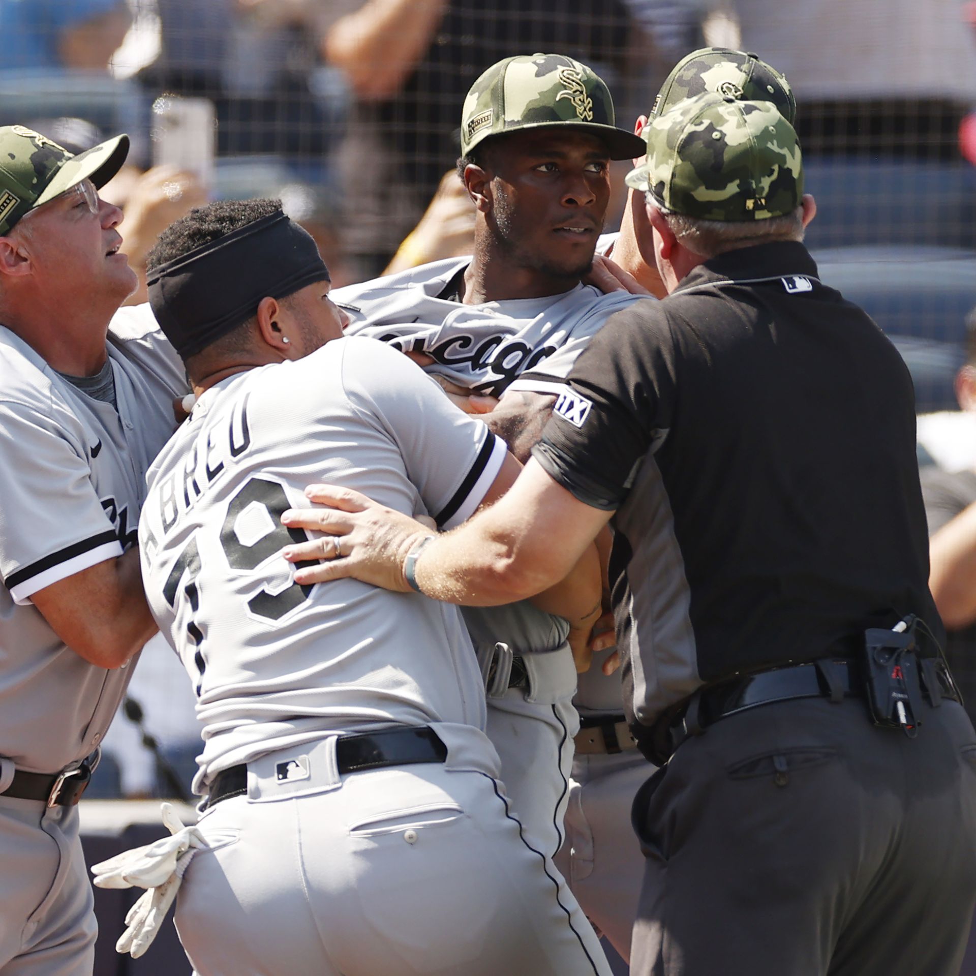 Photo of a baseball player being restrained from fighting. 