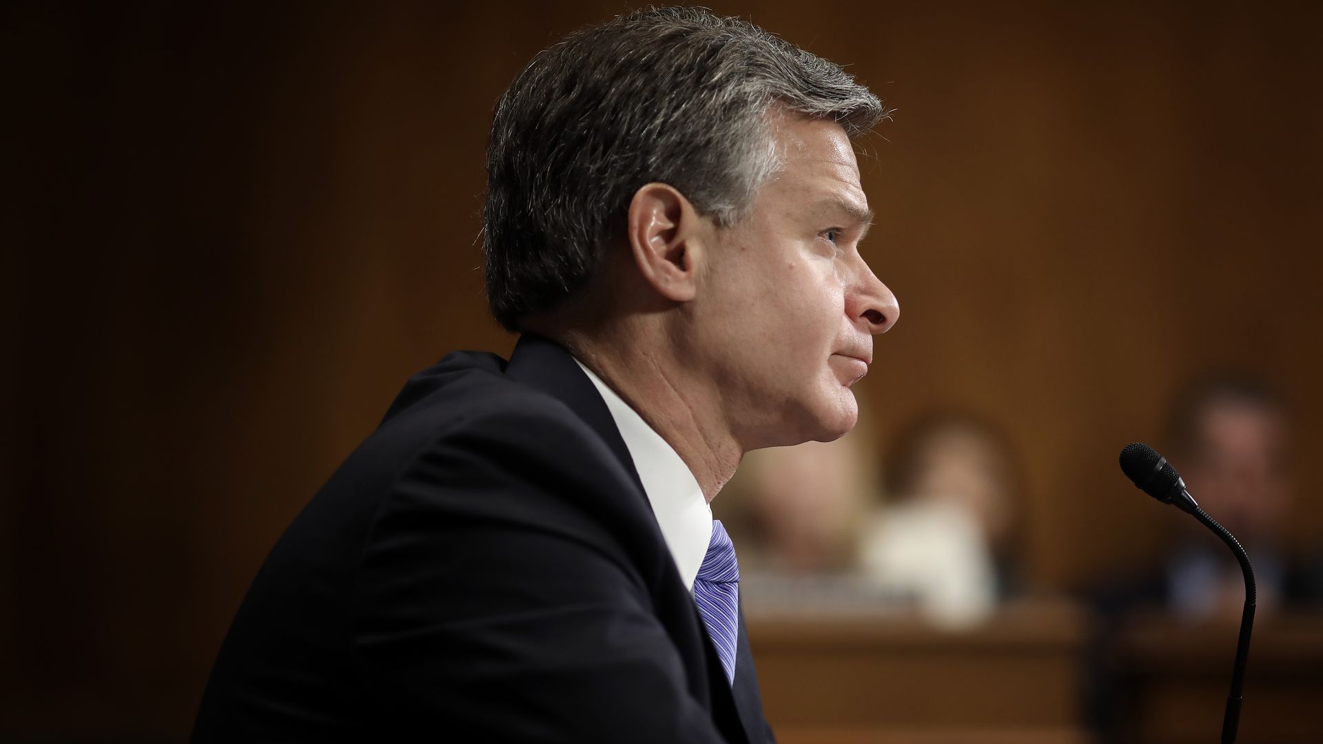 Wray sitting in his chair, facing the committee. 