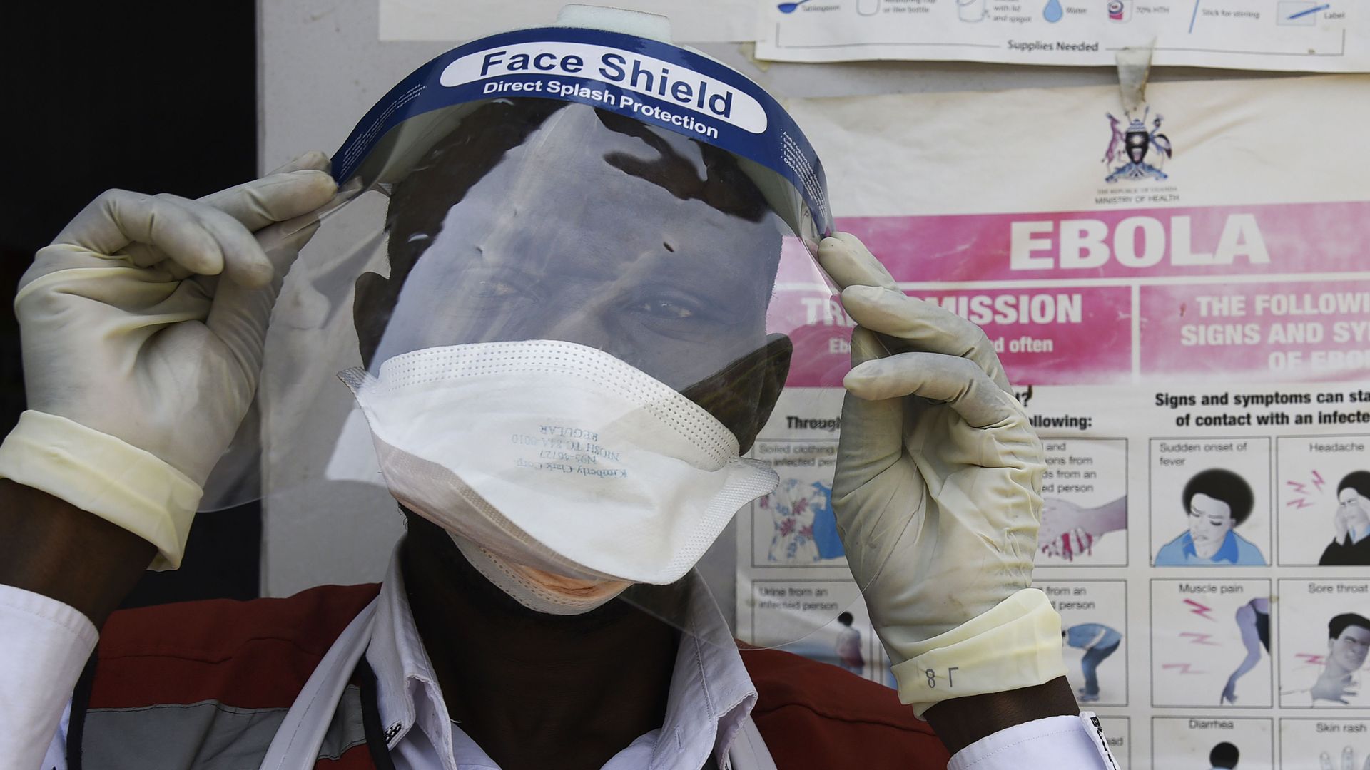 A health worker puts on protective gears as he prepares to screen travellers at the Mpondwe Health Screening Facility 