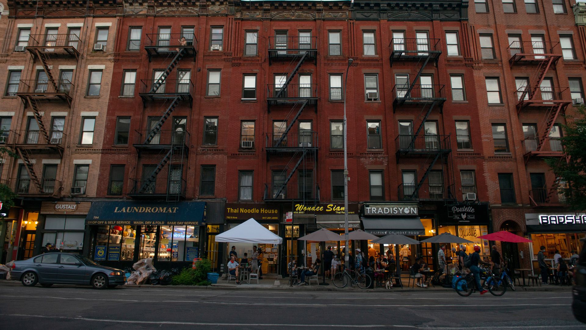 Photo of a red brick building with multiple storefronts on the first floor
