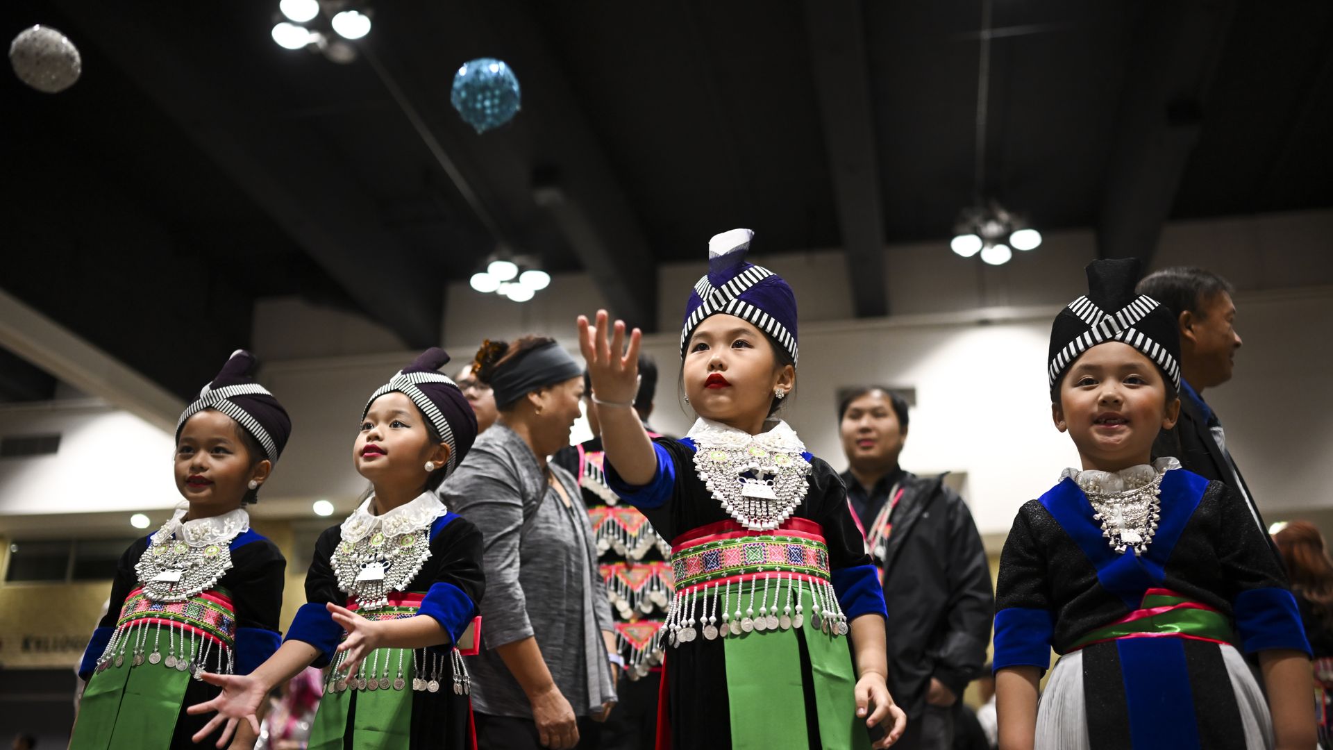 Young girls in traditional Hmong dress toss a ball while playing a game