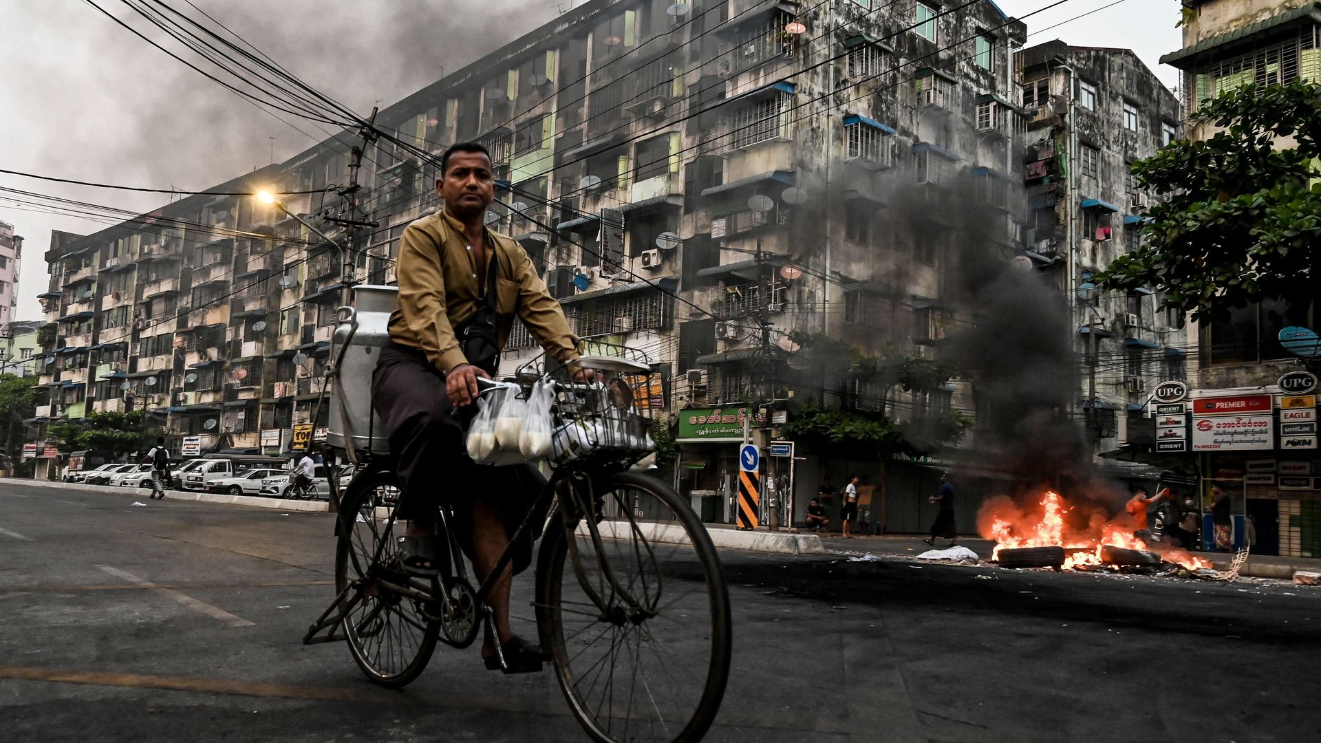 A man riding a bike near a fire in Yangon, Myanmar, on March 30.