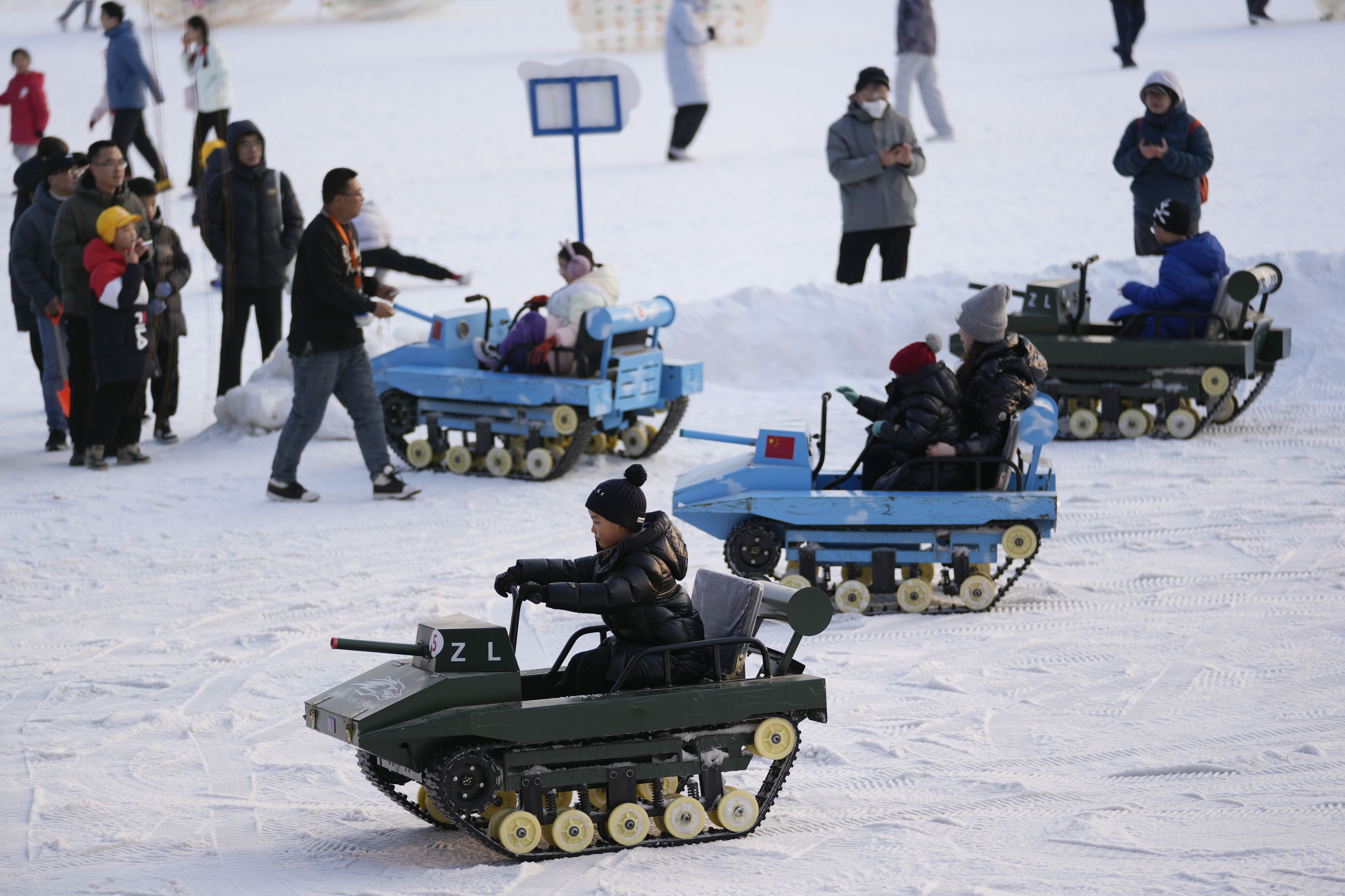 Children ride tank-styled snow carts on artificial snow at a park in Beijing yesterday, on the second day of Lunar New Year