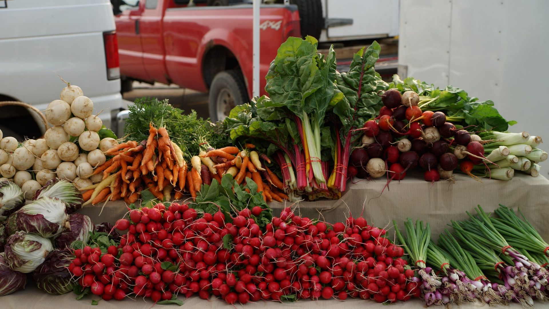 piles of produce on table with truck in background