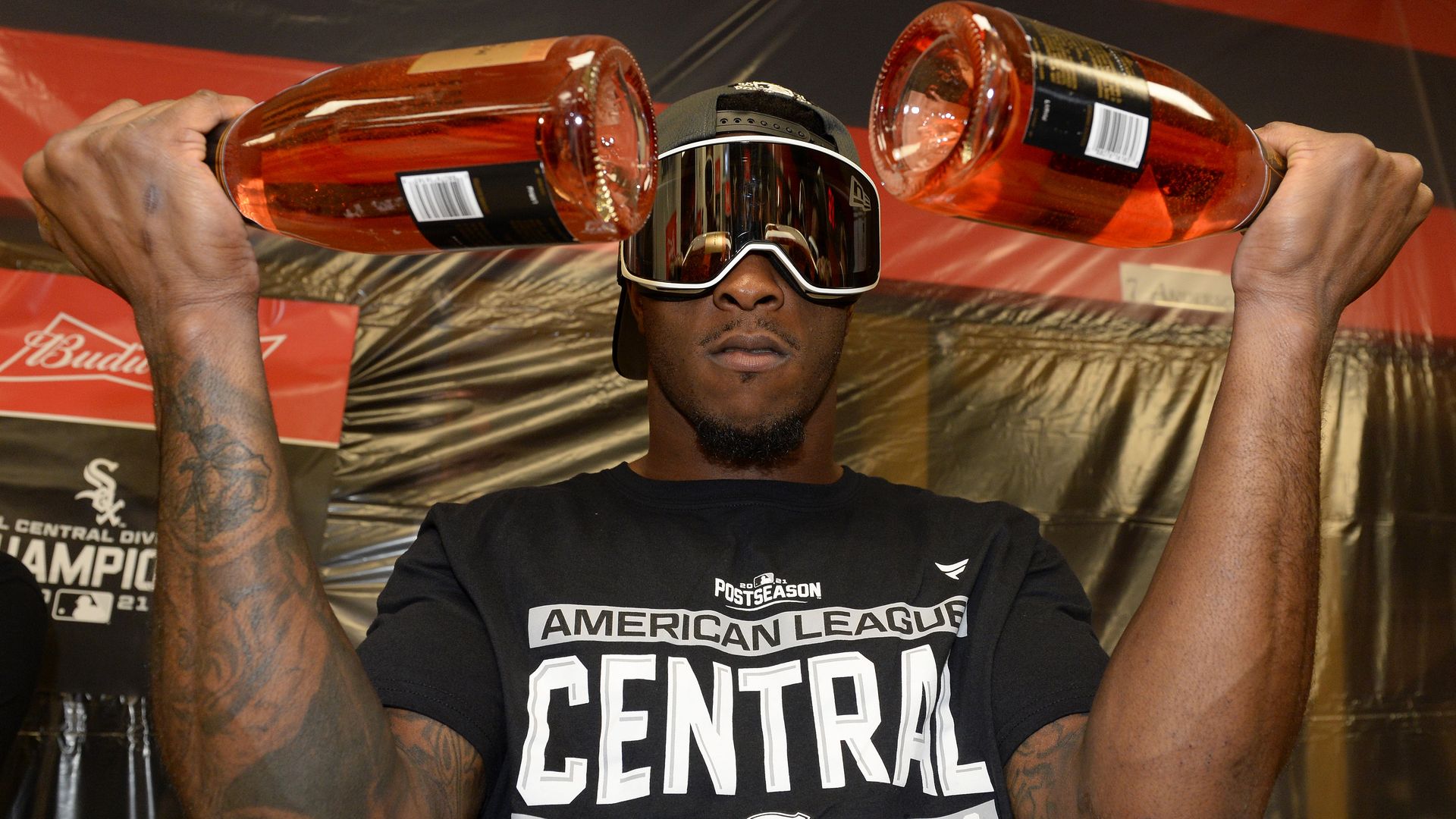 Photo of a baseball player celebrating with two bottles of wine in his hands and protective goggles on his face.