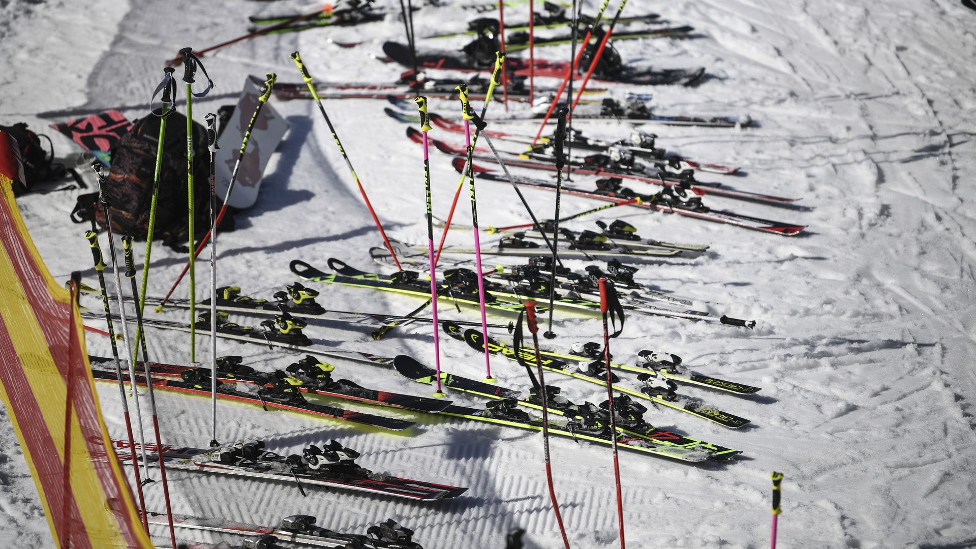 Dozens of skies with neon poles and one snowboard are left abandoned in snow.