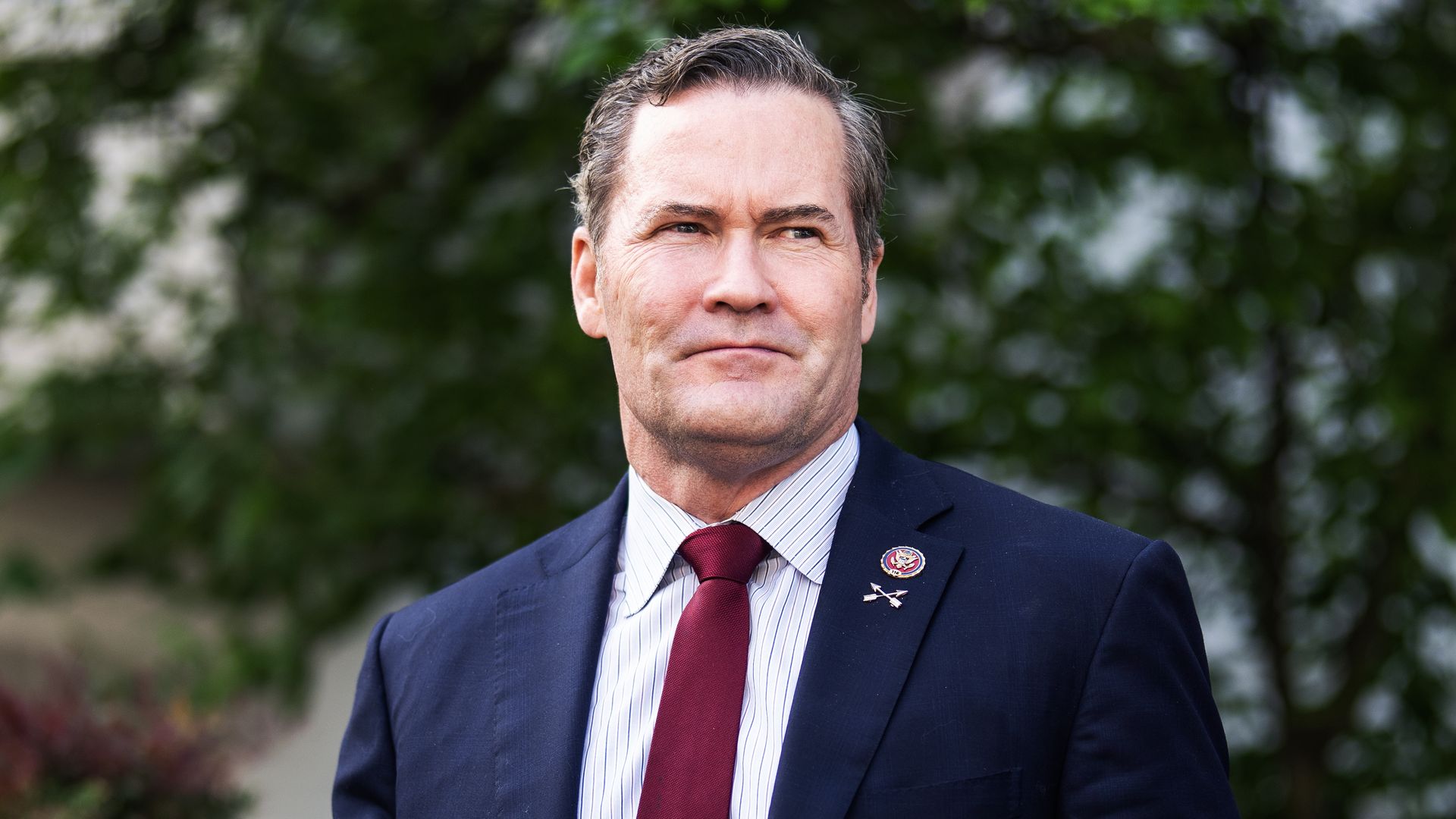 Rep. Michael Waltz, wearing a blue suit and standing in front of trees.