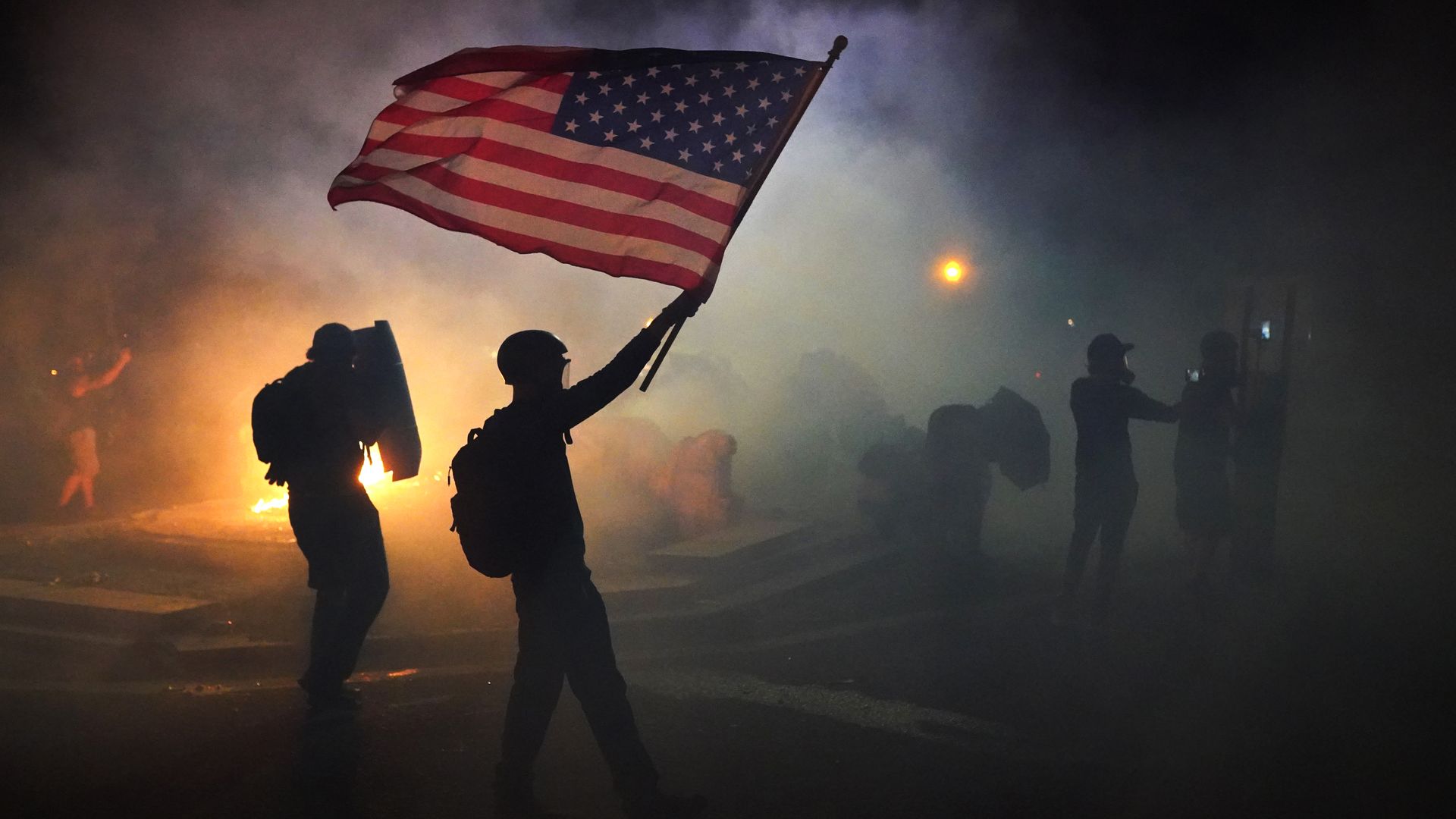 A protester flies an American flag while walking through tear gas fired by federal officers during a protest in front of the Mark O. Hatfield U.S. Courthouse on July 21, 2020 in Portland