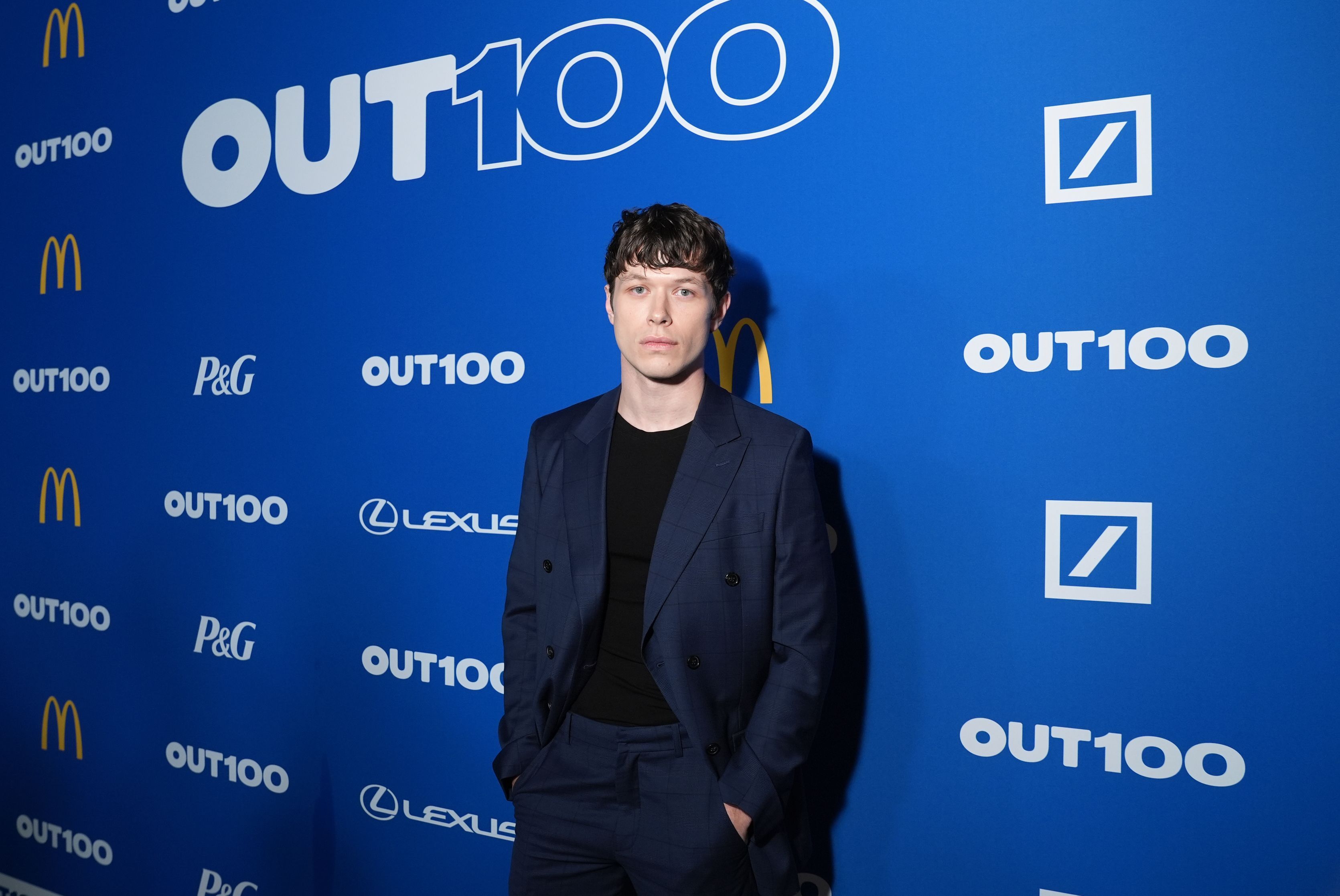 Photo of a man posing in front of a Out 100 billboard