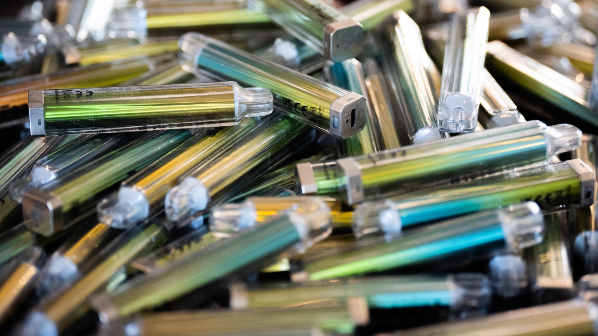 A pile of green, yellow and blue-colored vape pens with clear tops.
